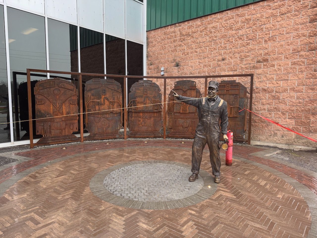 A statue of a man holding a fire extinguisher in front of a building.