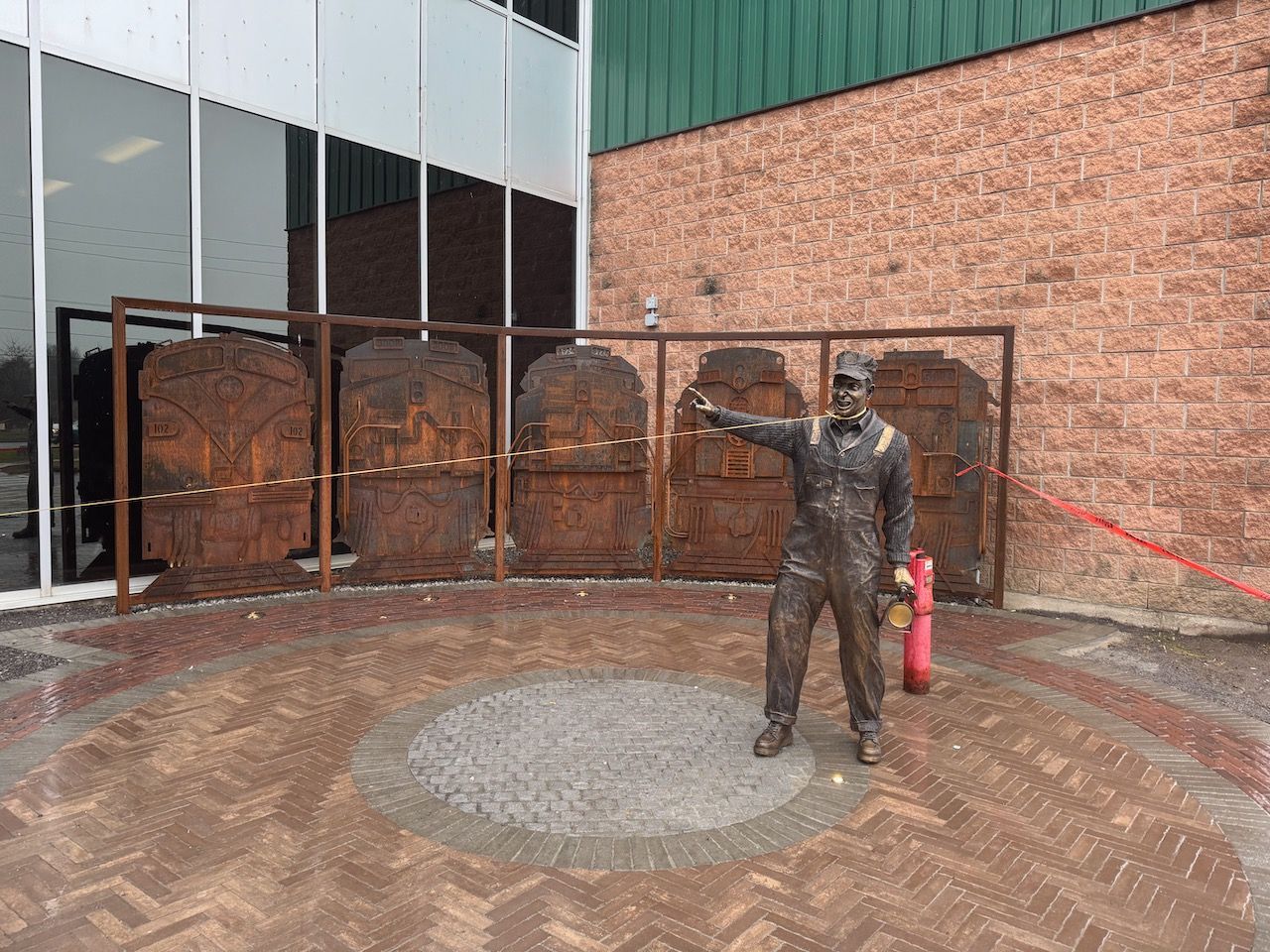 A statue of a man holding a fire extinguisher in front of a building.