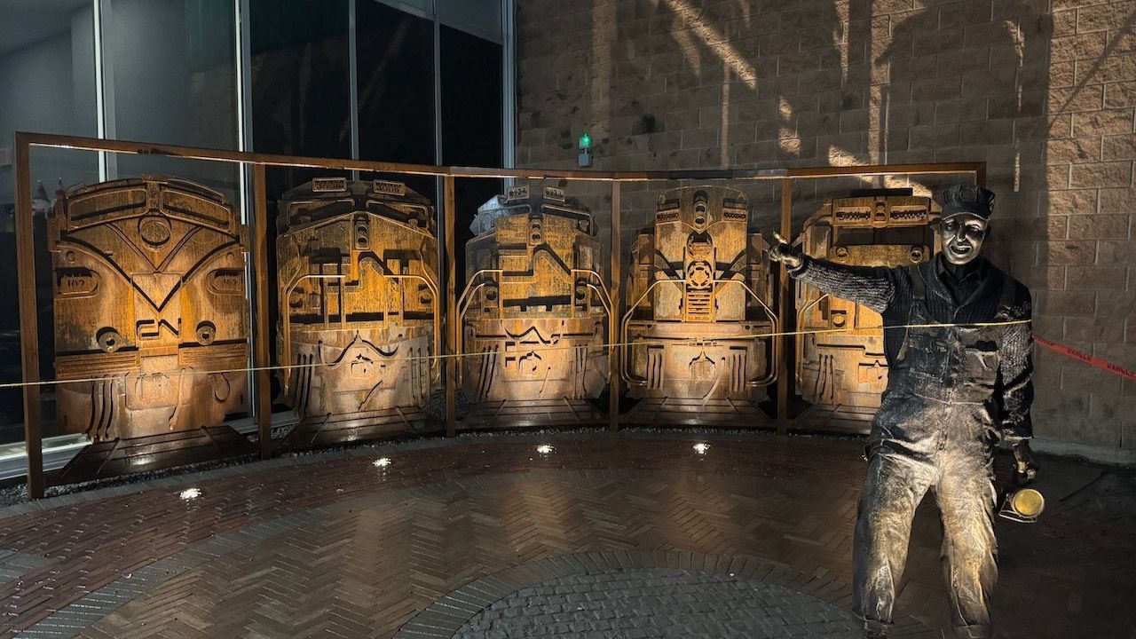 A man is standing in front of a wall of sculptures.