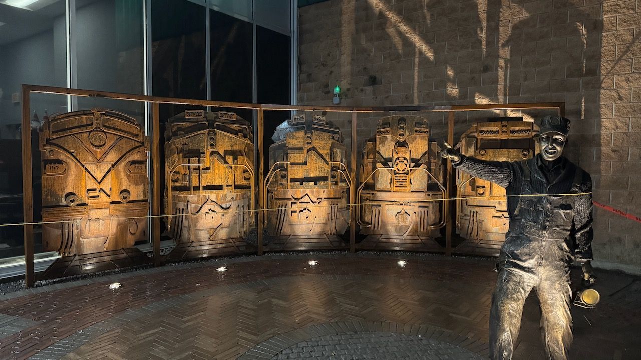 A man in a mask is standing in front of a fence in a room.