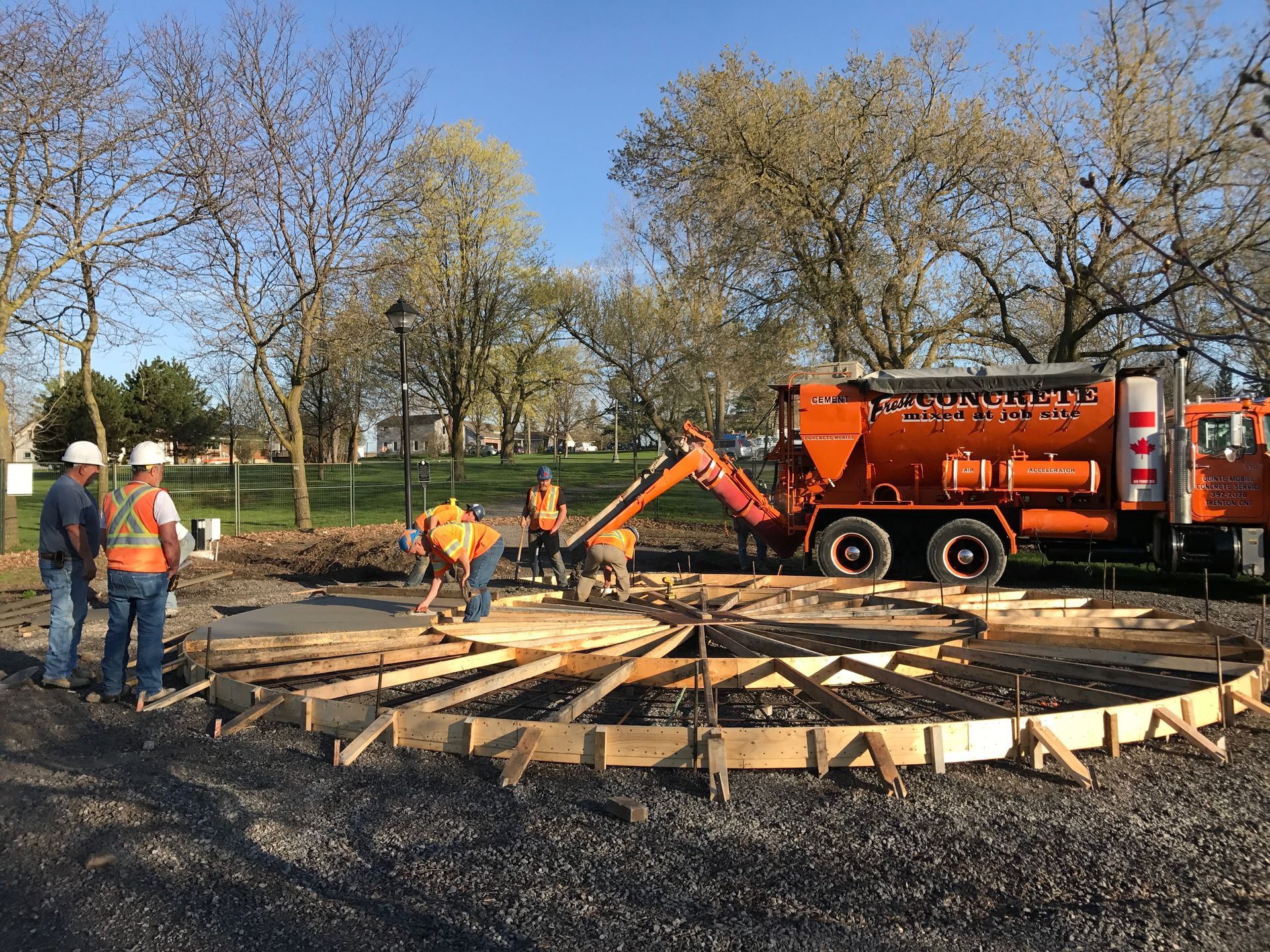 A group of construction workers are standing in front of an orange truck.
