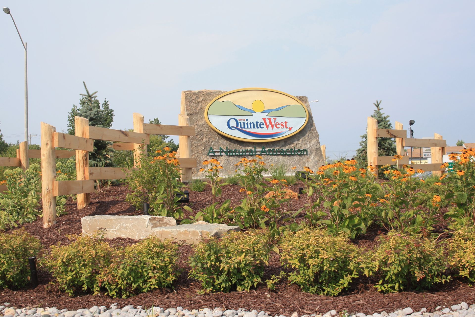 A sign for quiet west is surrounded by bushes and a wooden fence
