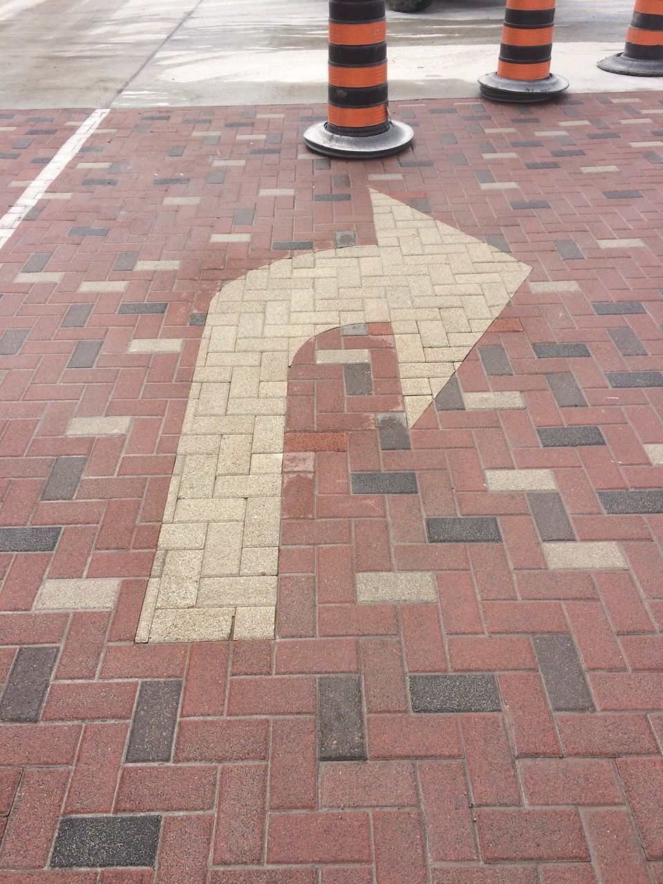 A white arrow is painted on a brick pavement