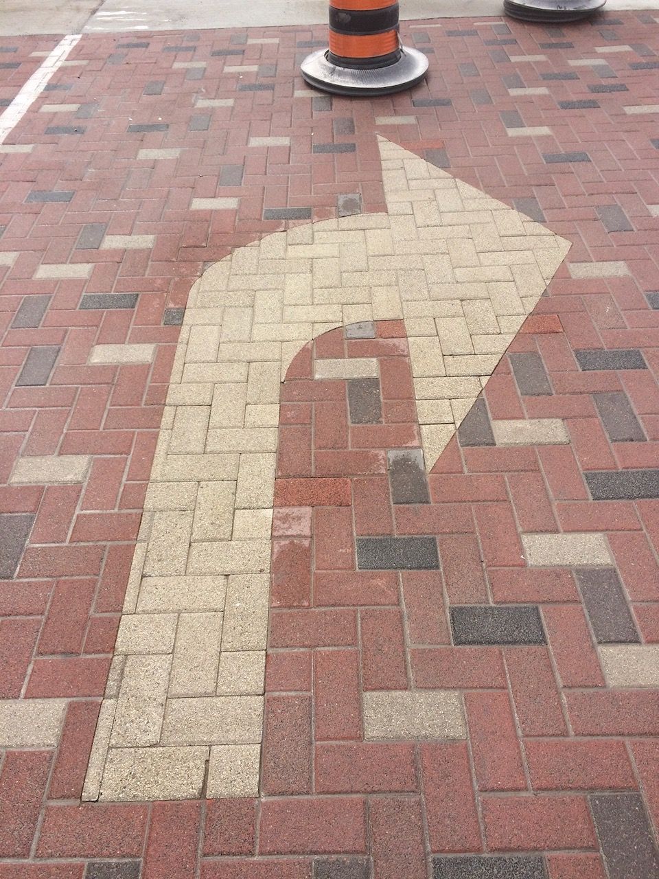 A white arrow is painted on a brick sidewalk