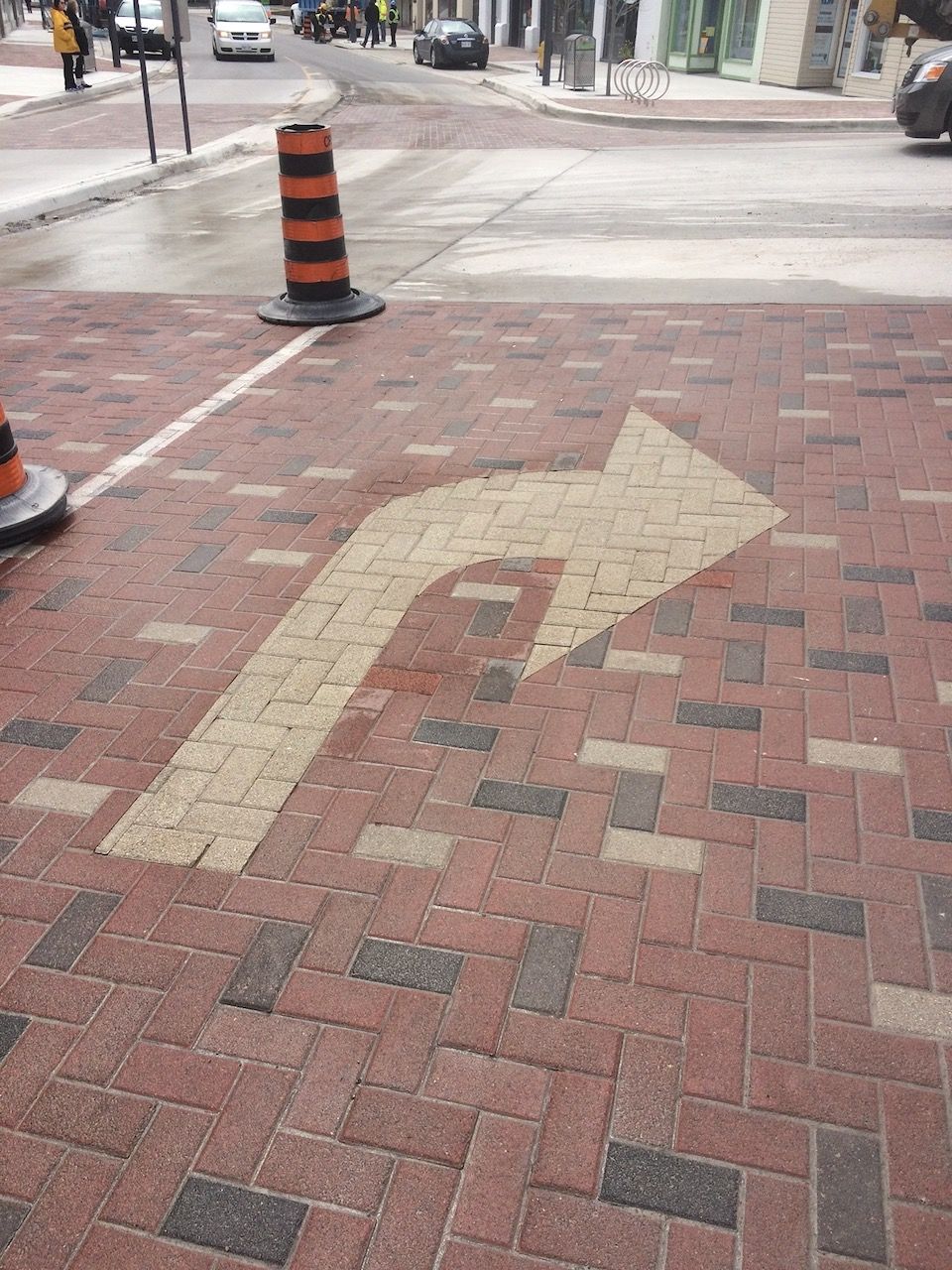 A brick sidewalk with an arrow painted on it