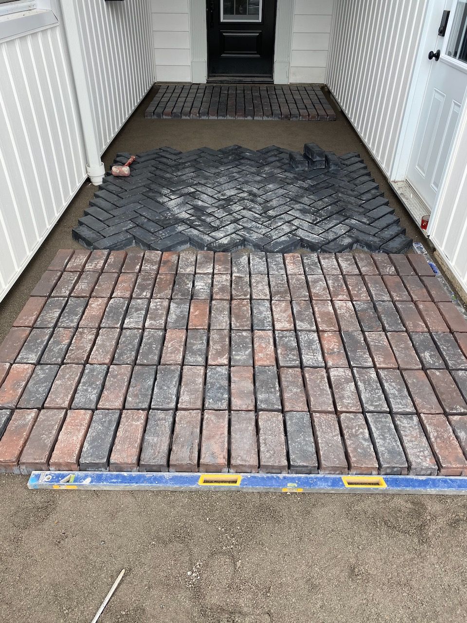 A brick walkway is being built in front of a house.