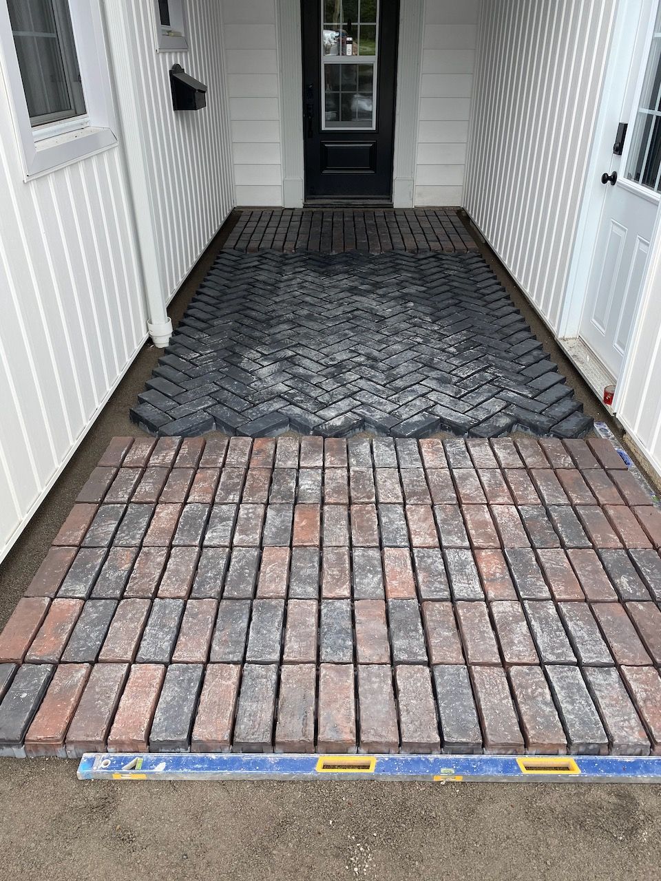A brick walkway is being built in front of a house.
