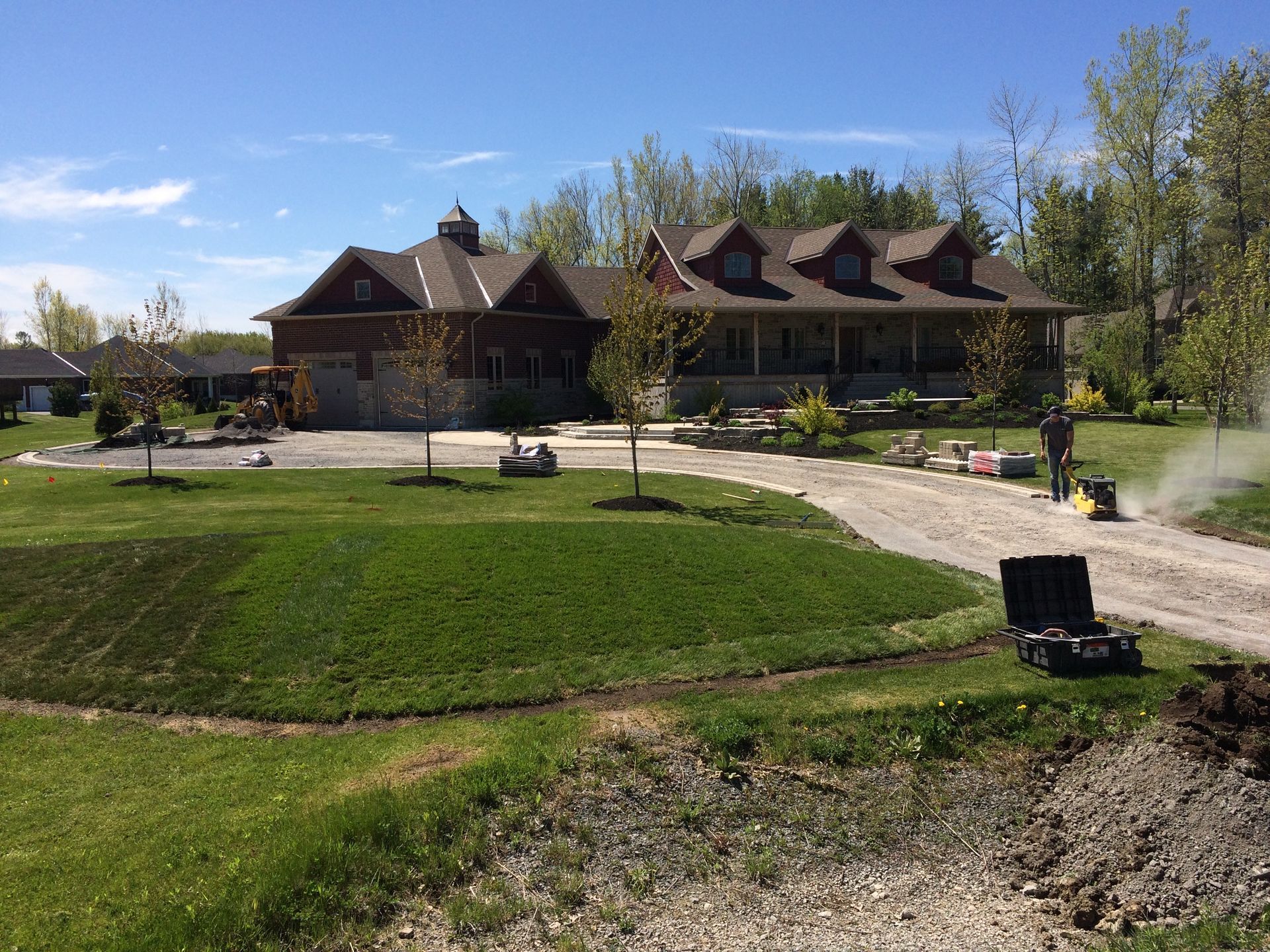 A large house is sitting in the middle of a lush green field.