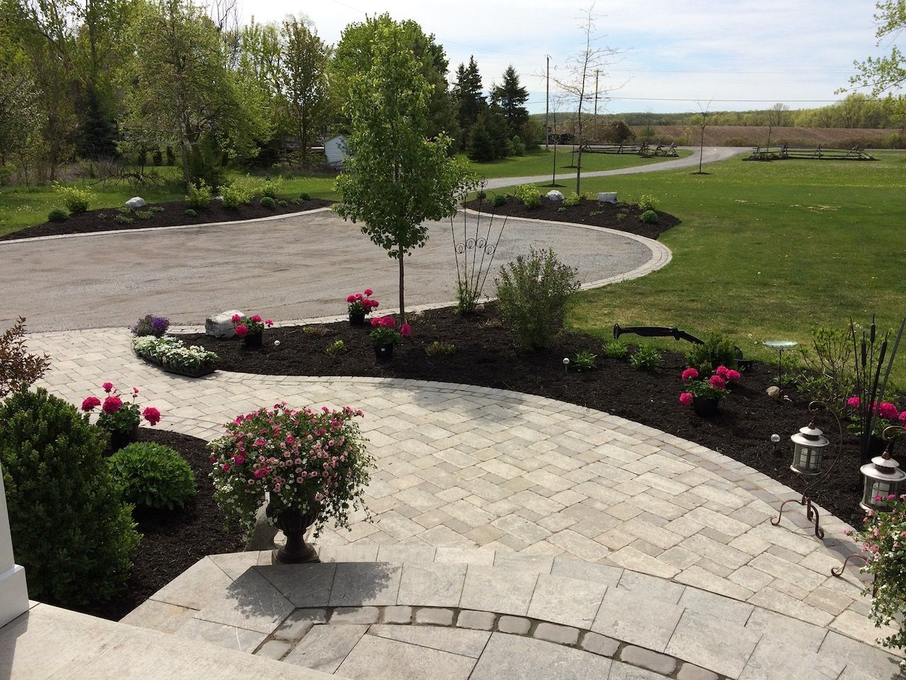 A patio with flowers and a driveway in the background