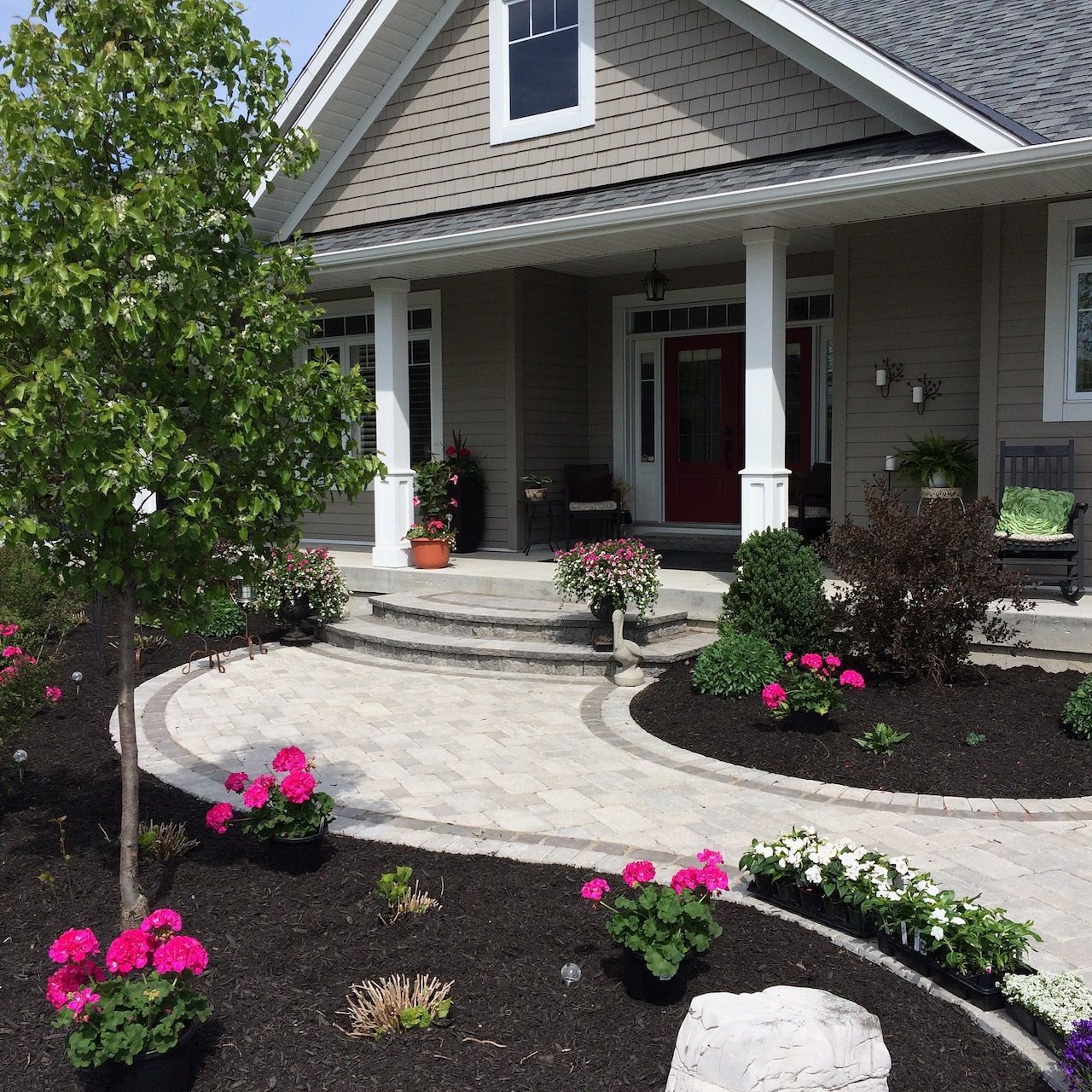 The front of a house with flowers and trees in front of it