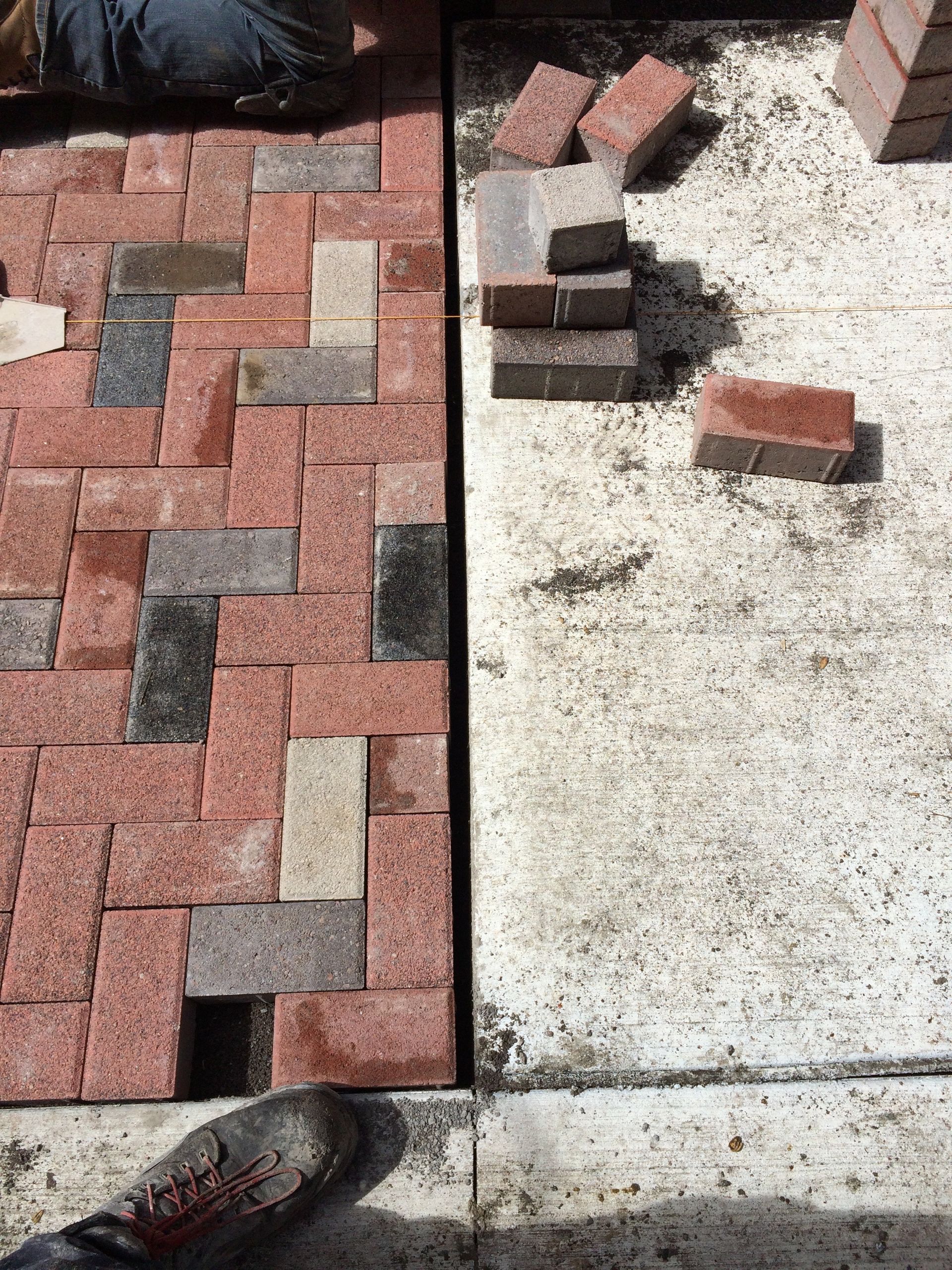 A person is laying bricks on a concrete surface.