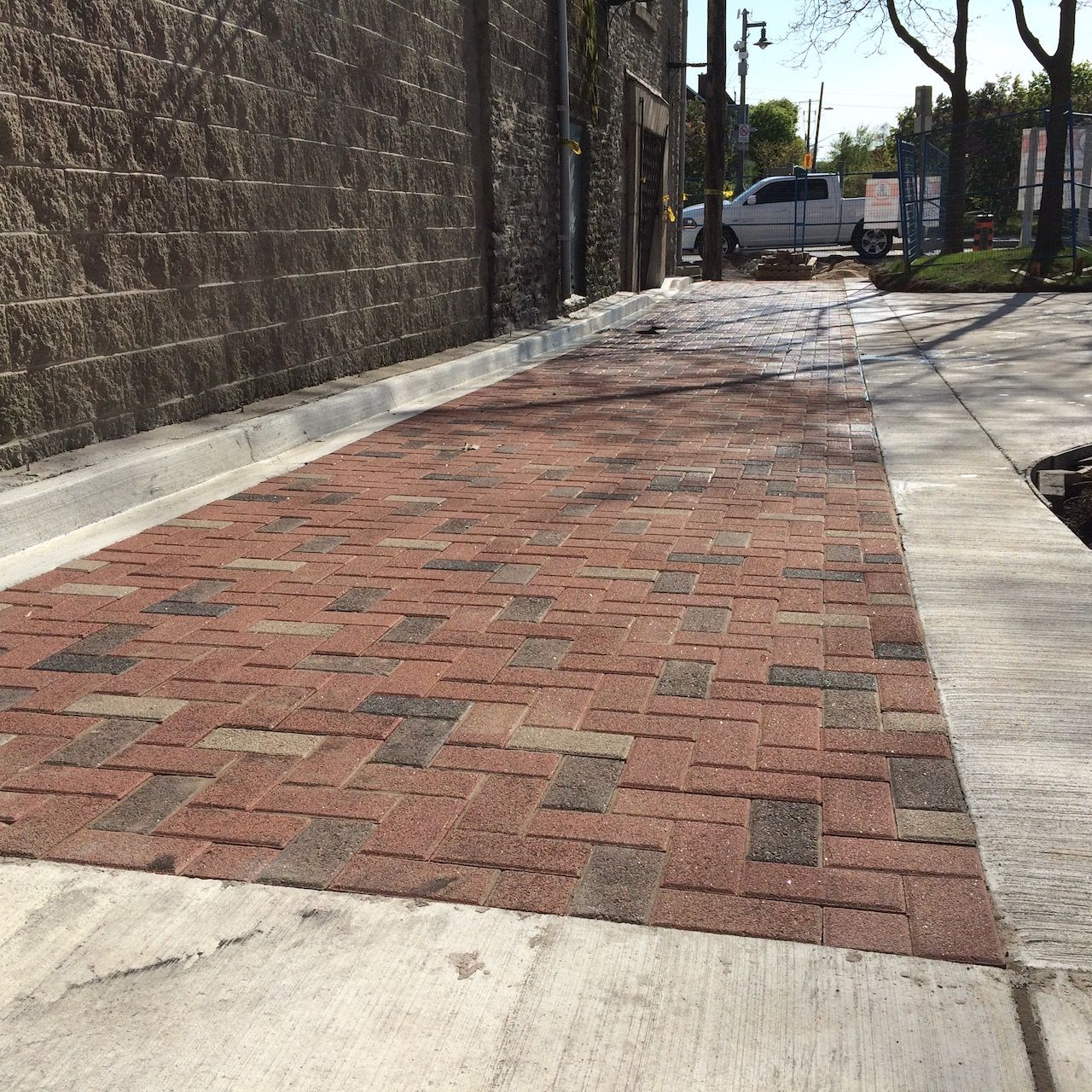 A brick walkway with a concrete curb and a brick wall in the background