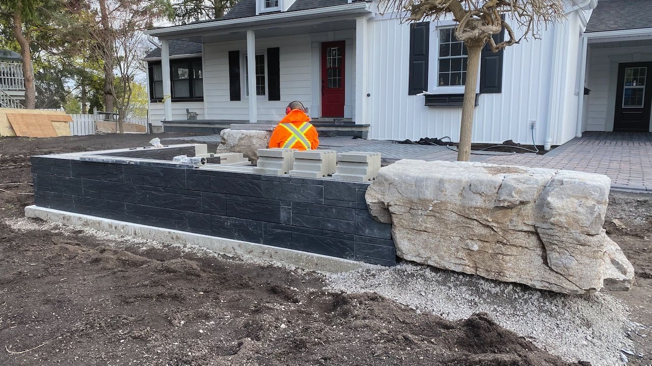 A large rock is sitting in front of a white house.