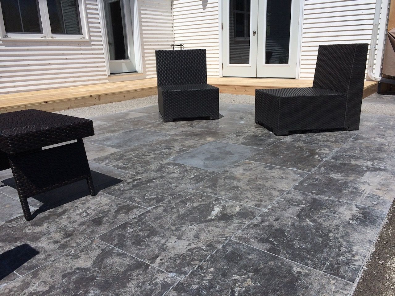 A patio with chairs and a table in front of a house.