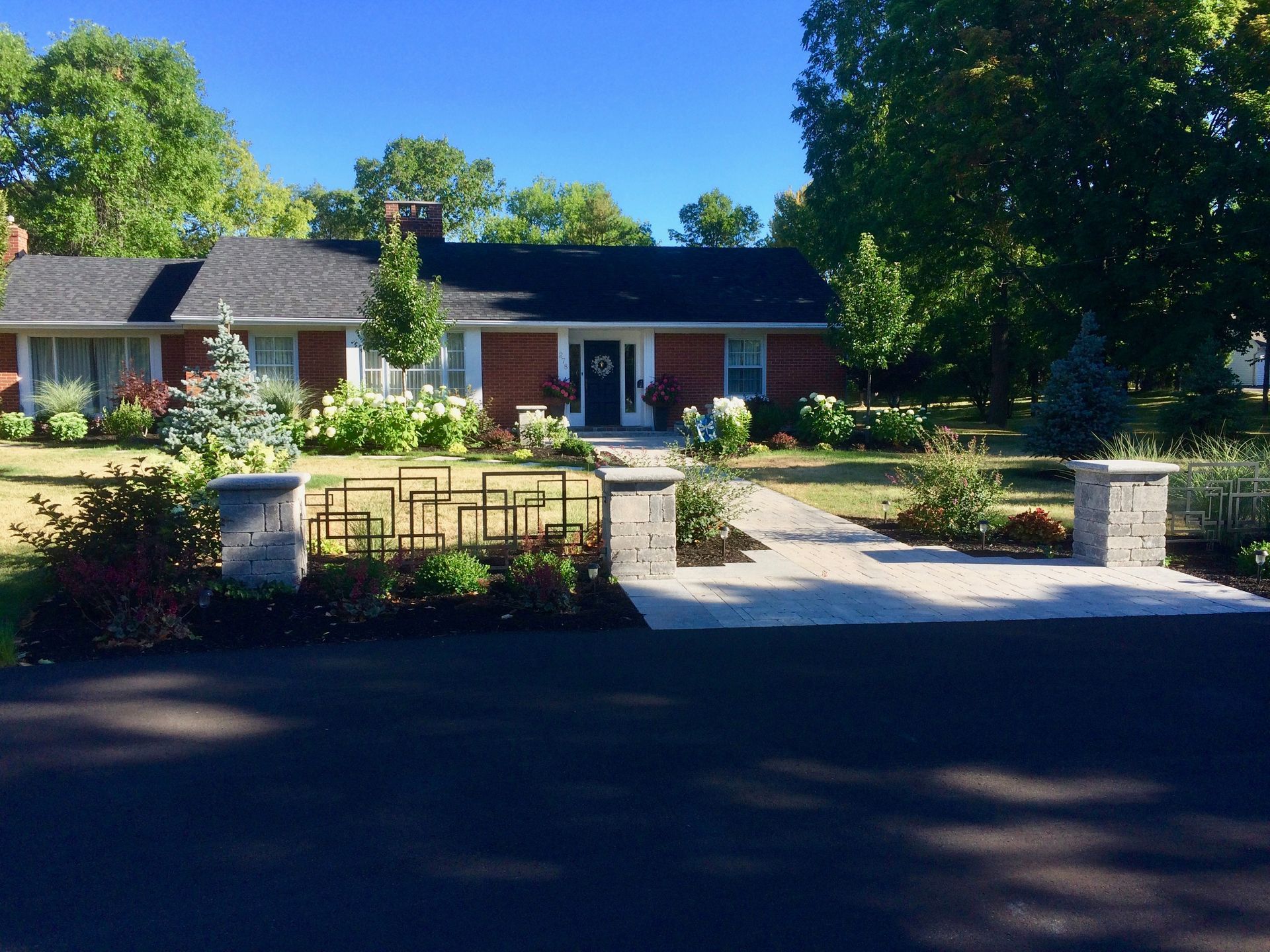 A brick house with a black roof and a black driveway