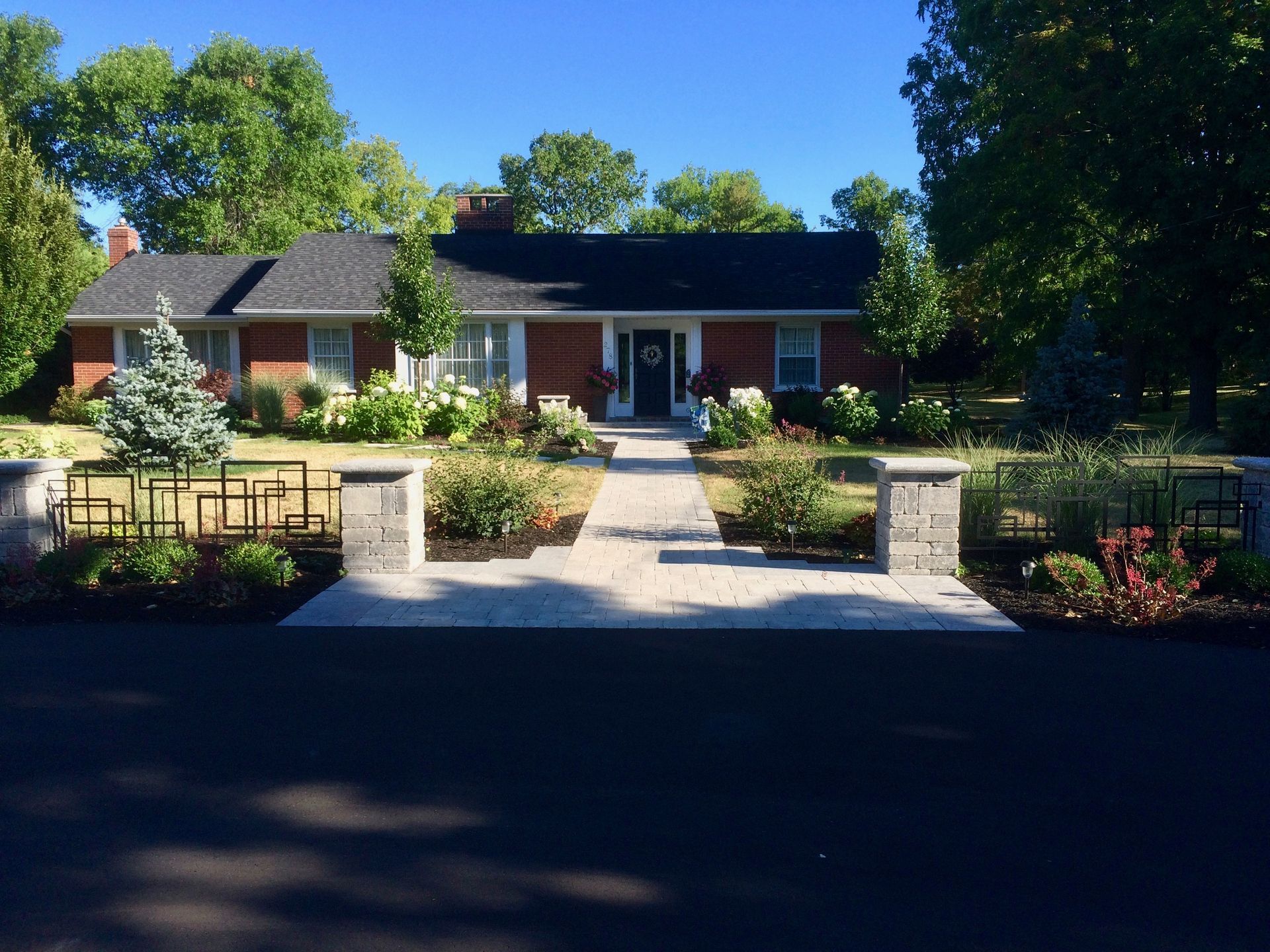 A brick house with a black roof and a walkway leading to it