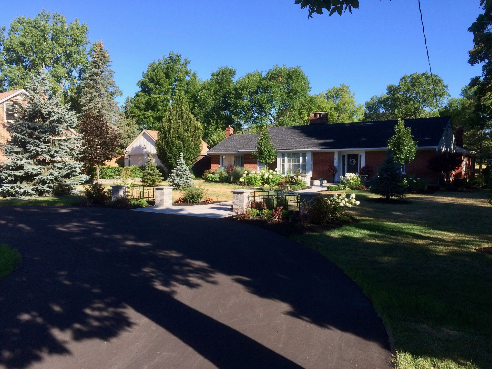 A driveway leading to a brick house with a black roof