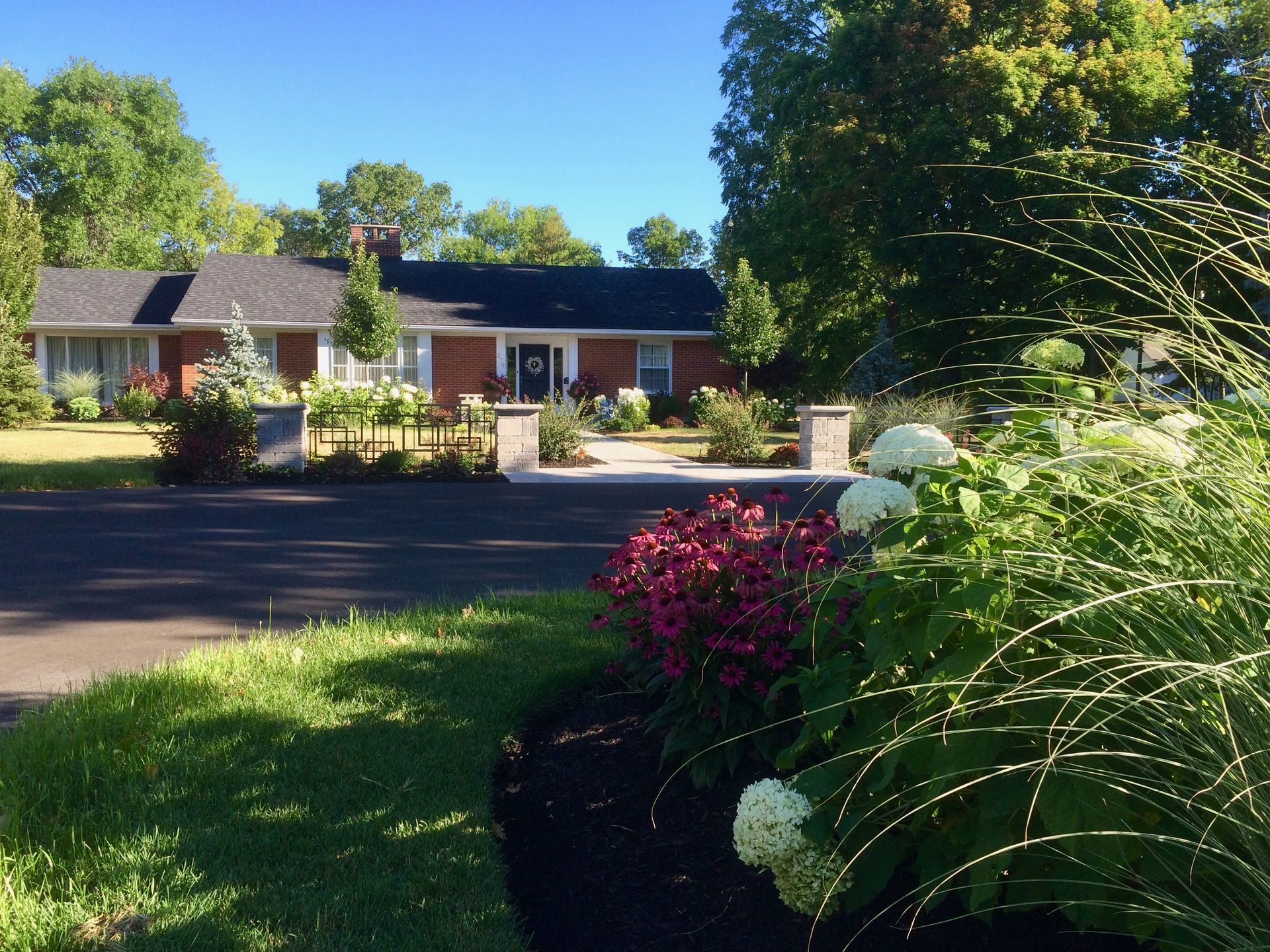 A brick house with a driveway and flowers in front of it