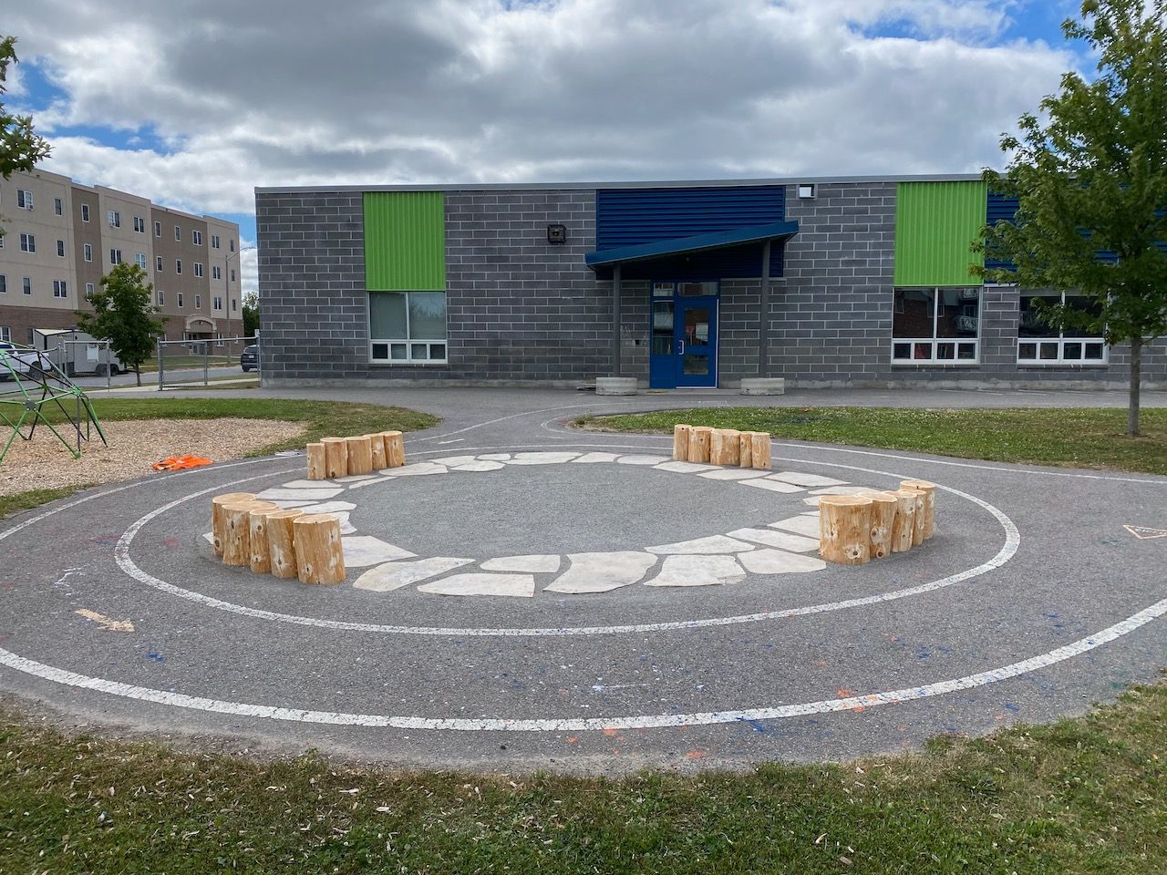 A group of logs are sitting in a circle in front of a building.