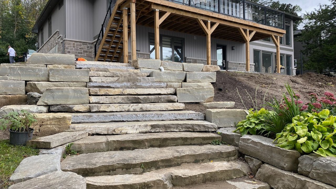 A stone staircase leading up to a house with a wooden deck.