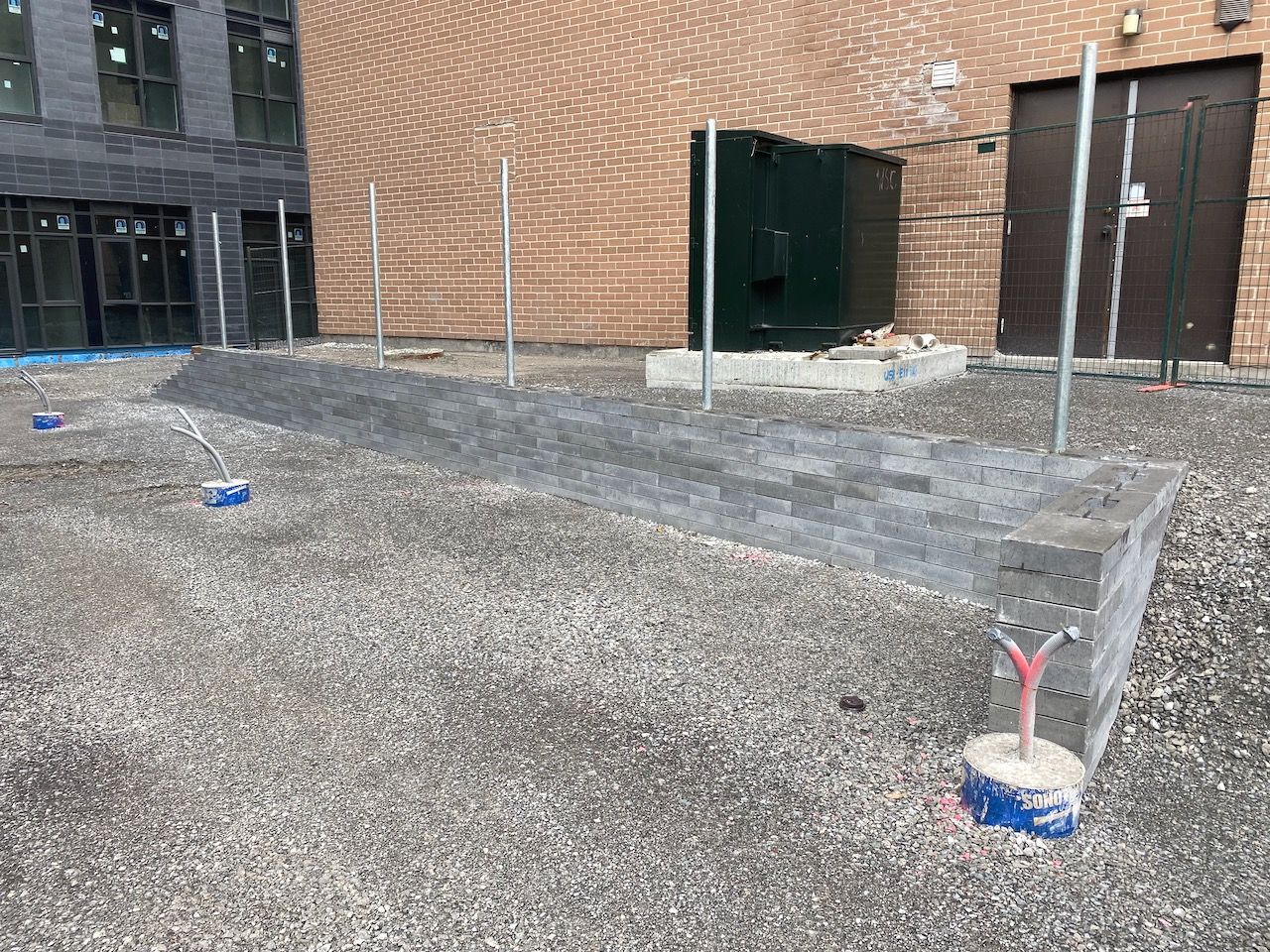 A brick building is being built next to a gravel area.