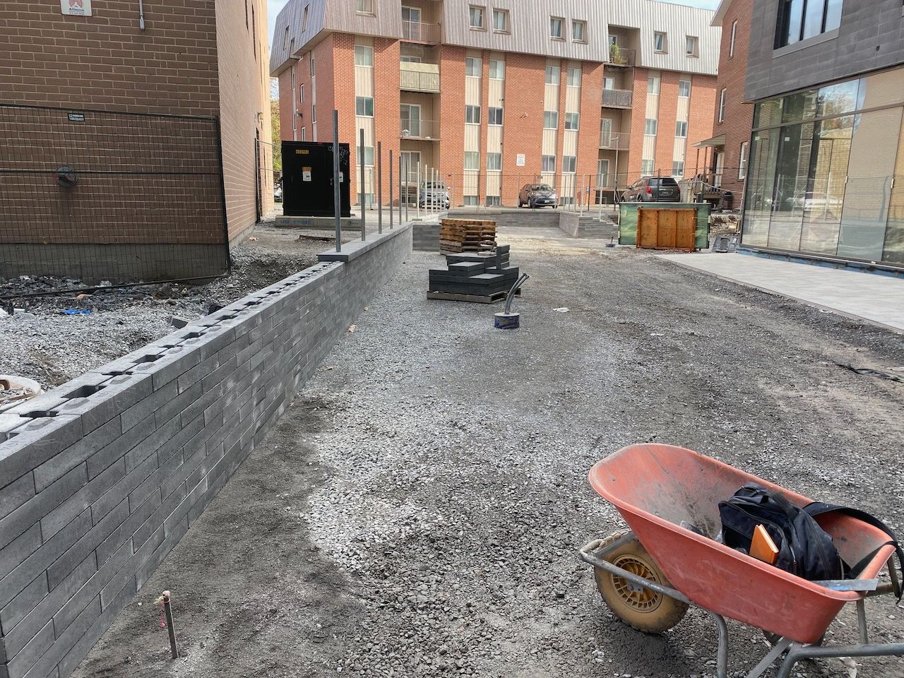 A wheelbarrow is sitting on the ground in front of a building under construction.