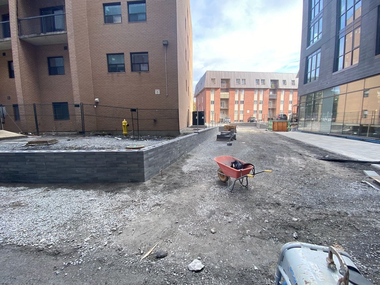 A wheelbarrow is sitting in the dirt in front of a building under construction