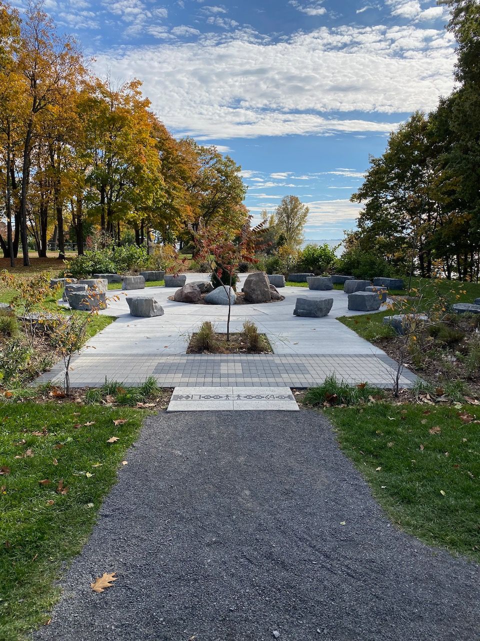 A path in a park surrounded by trees and grass on a sunny day.