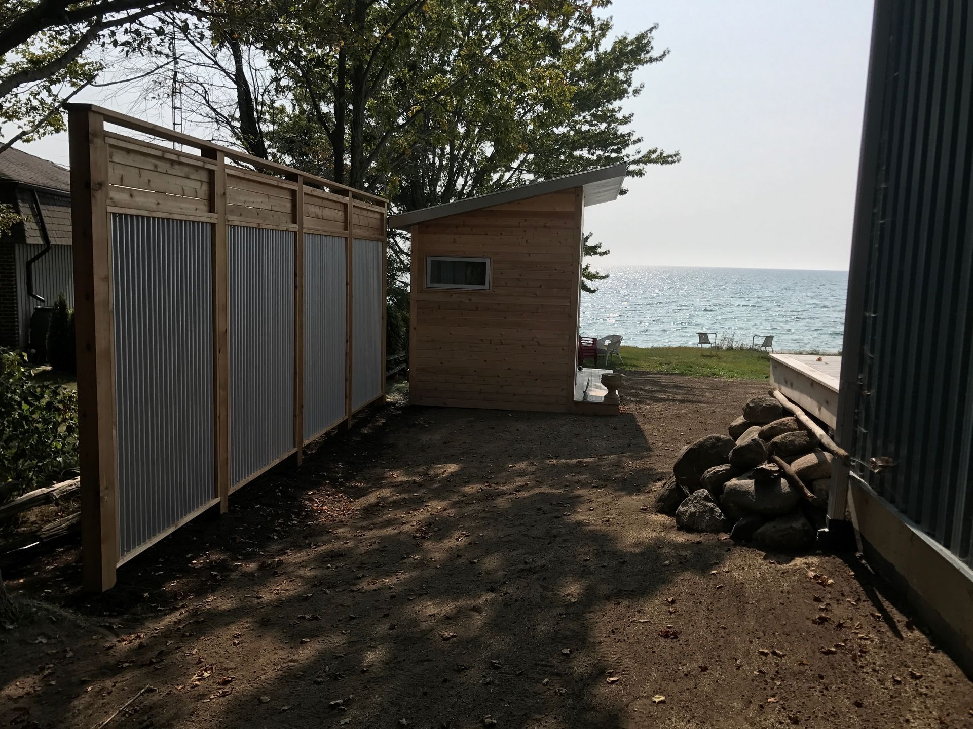 A wooden shed sits next to a fence with a view of the ocean