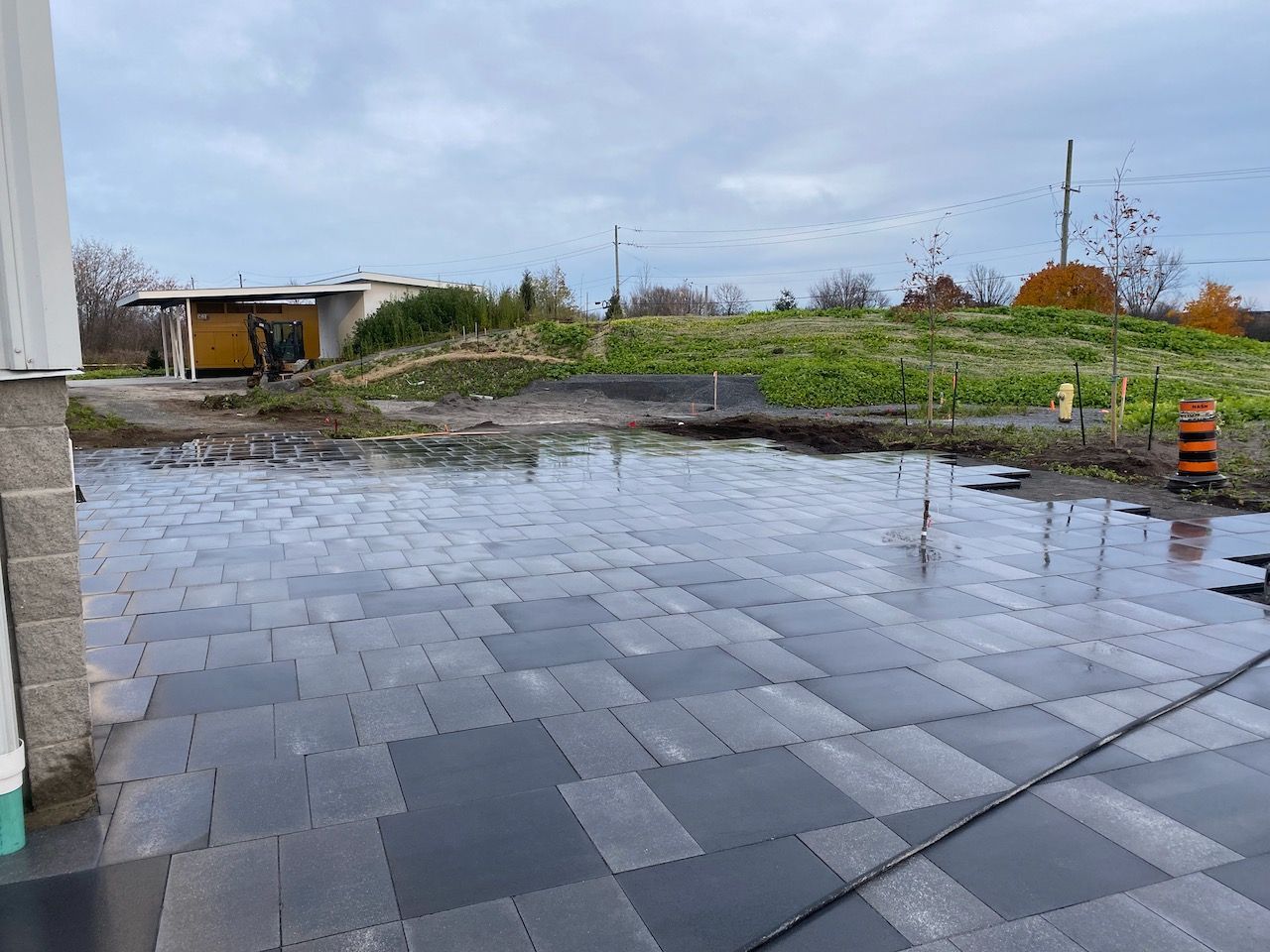 A large puddle of water is sitting in the middle of a brick driveway.