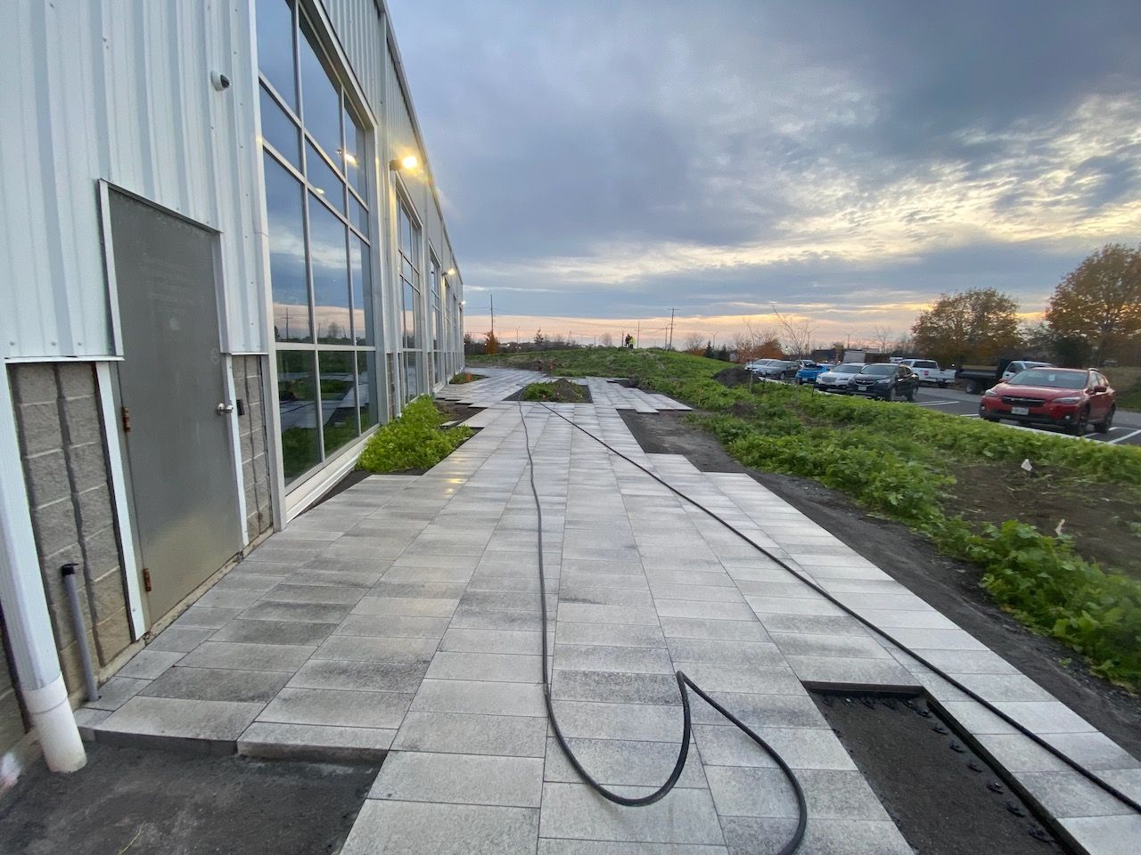 A hose is connected to a sidewalk in front of a building.