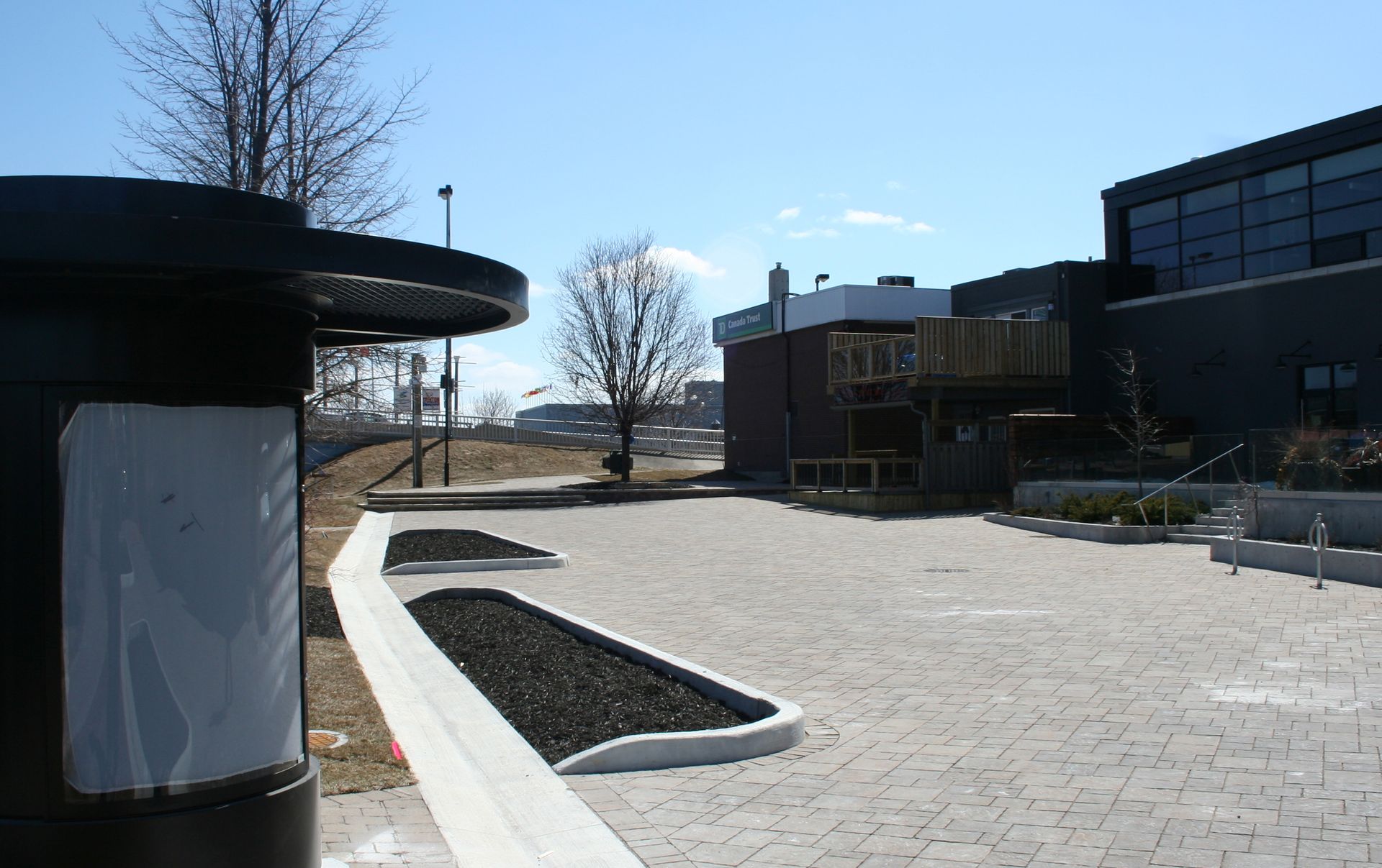 A parking lot with a building in the background and a trash can in the foreground