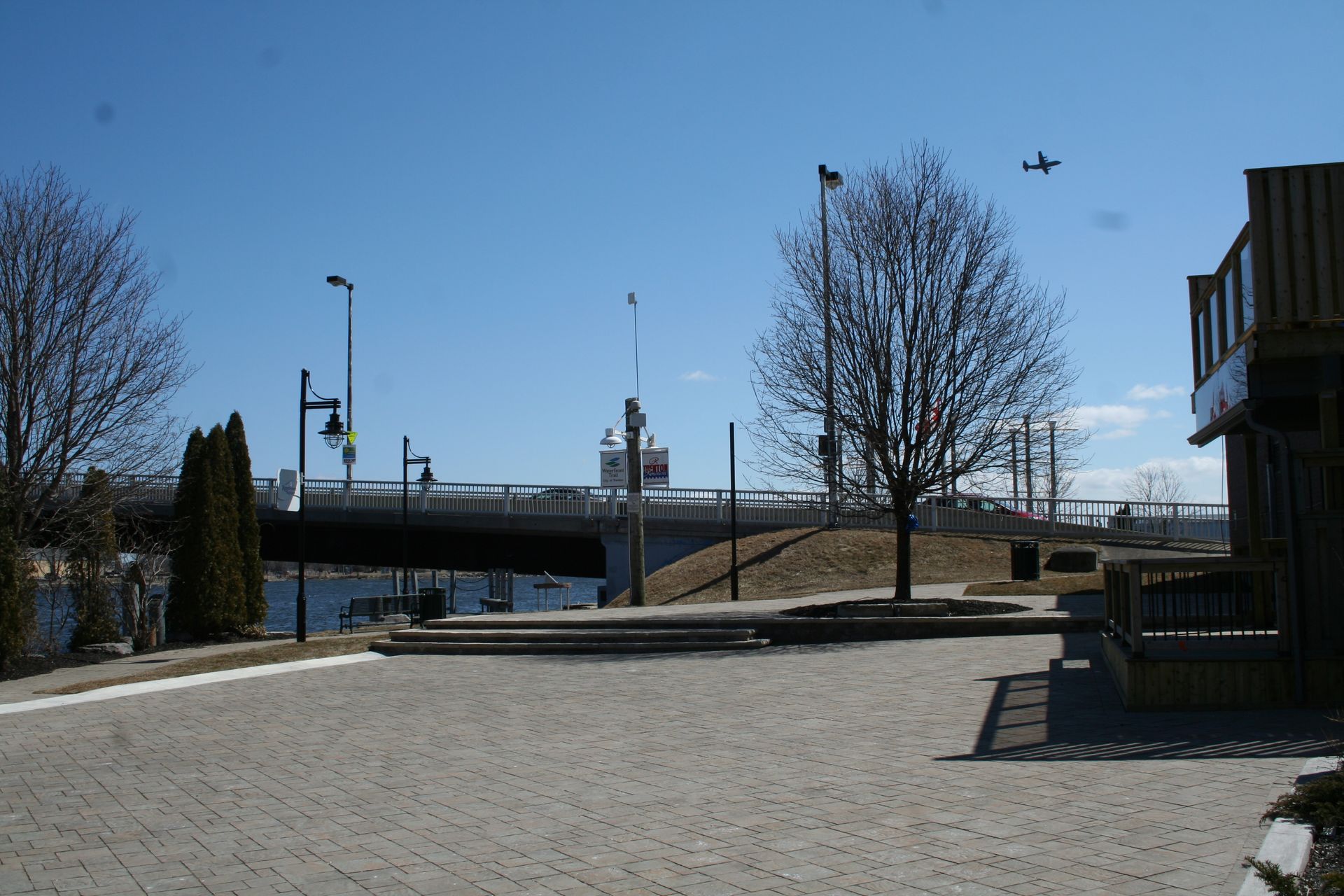 A plane is flying over a bridge in the distance