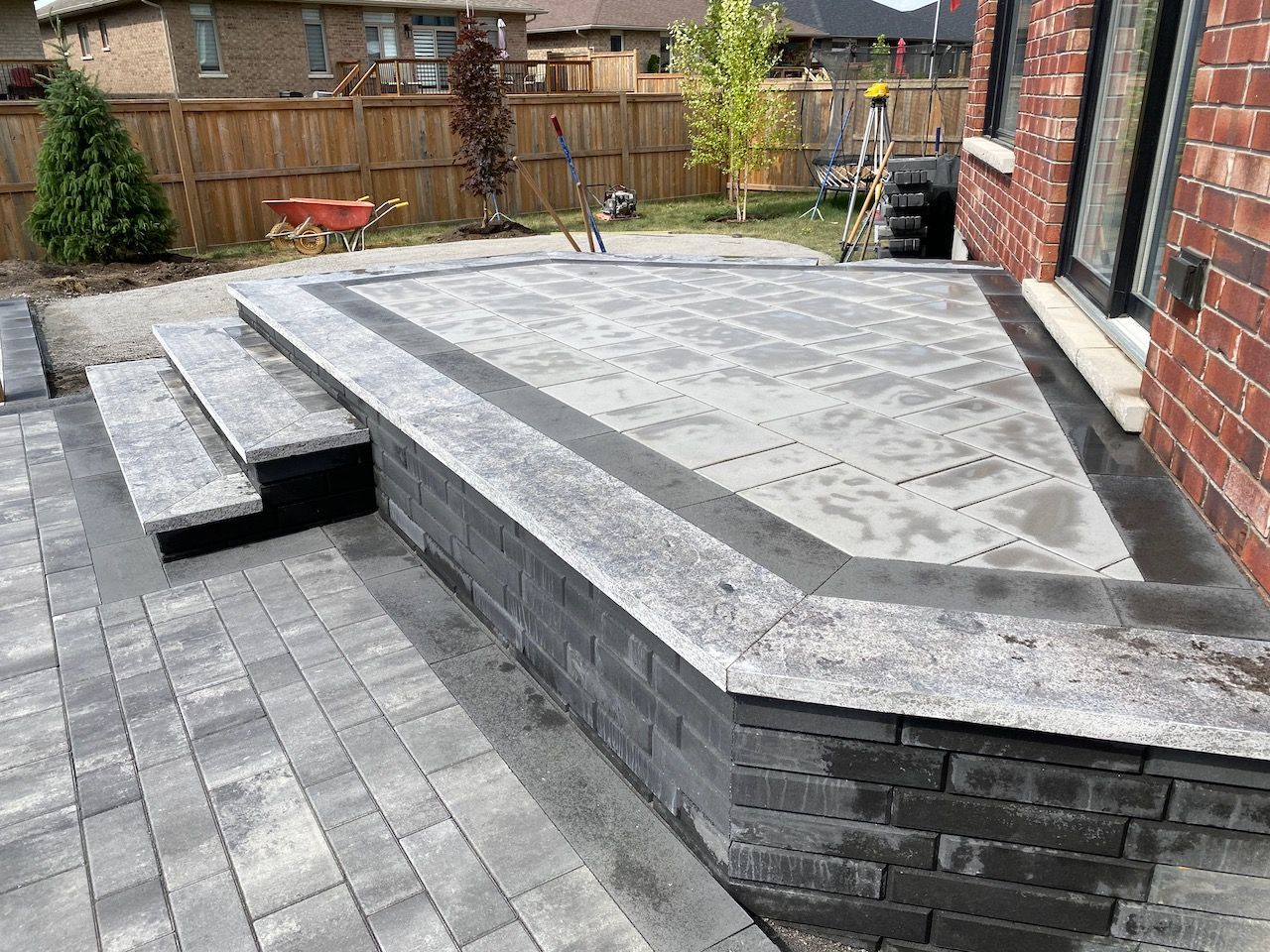 A patio with stairs and a brick wall in front of a brick house.