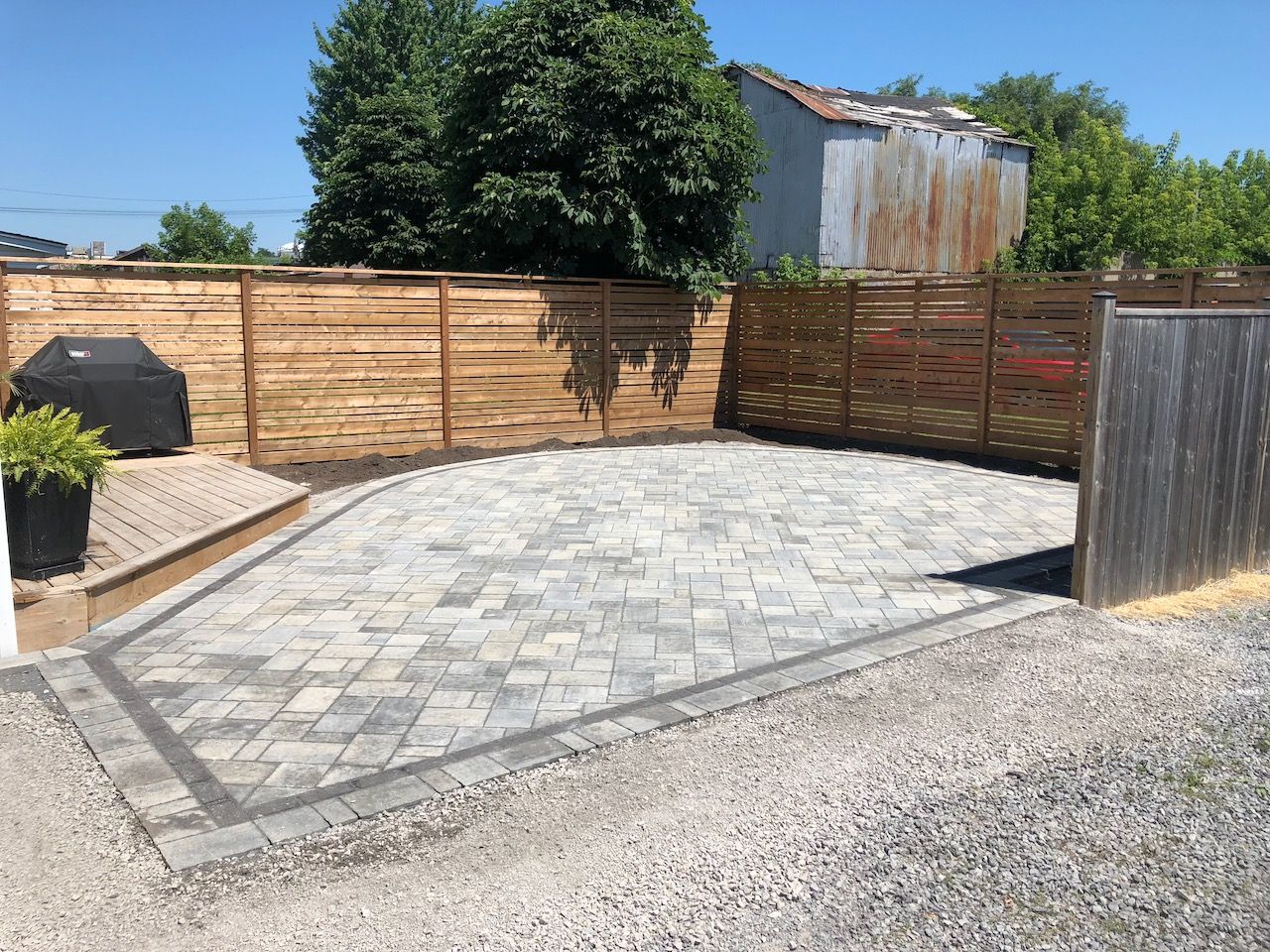 A backyard with a brick patio and a wooden fence.