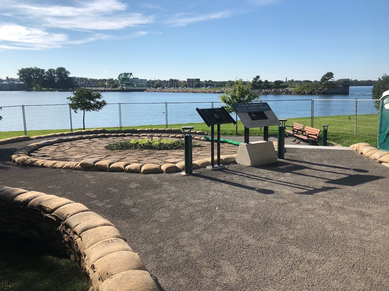 A park with a sign in the middle of it and a lake in the background.