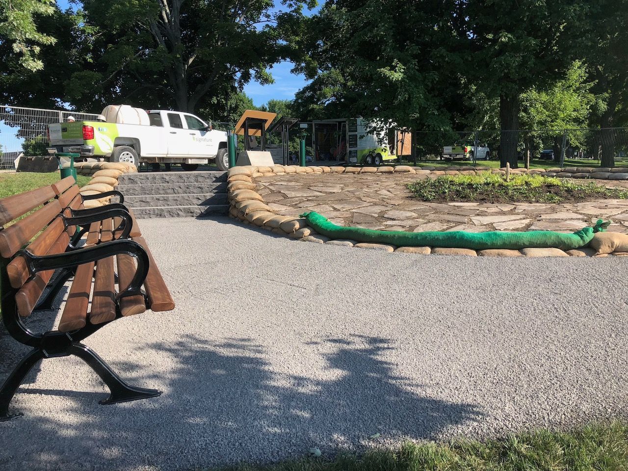 A bench in a park with a truck parked in the background