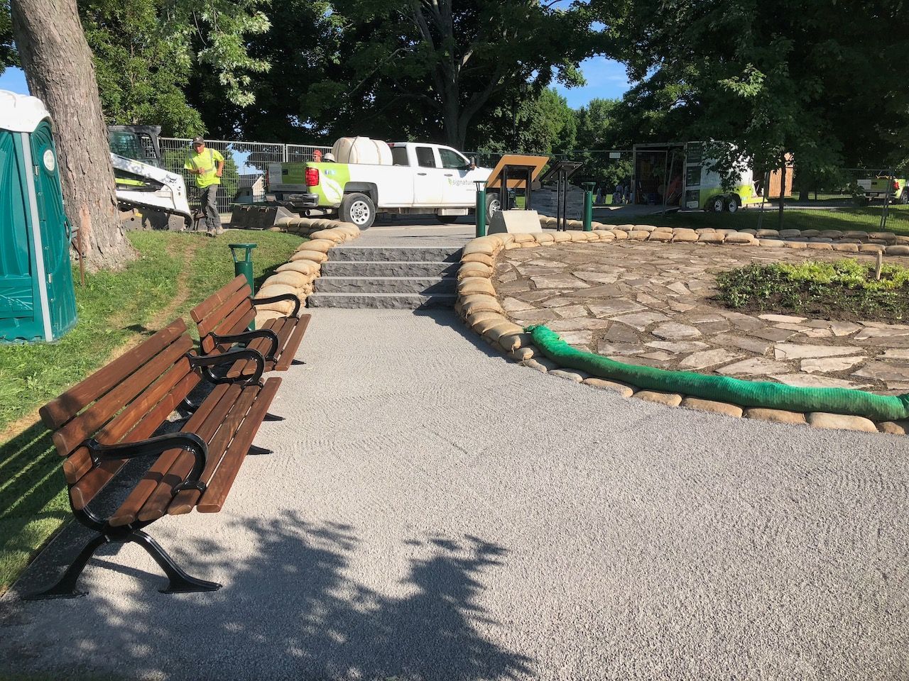 A wooden bench is sitting on a gravel path in a park.