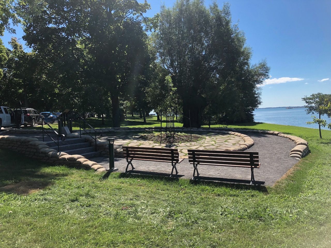 Two wooden benches are sitting in a park next to a body of water.