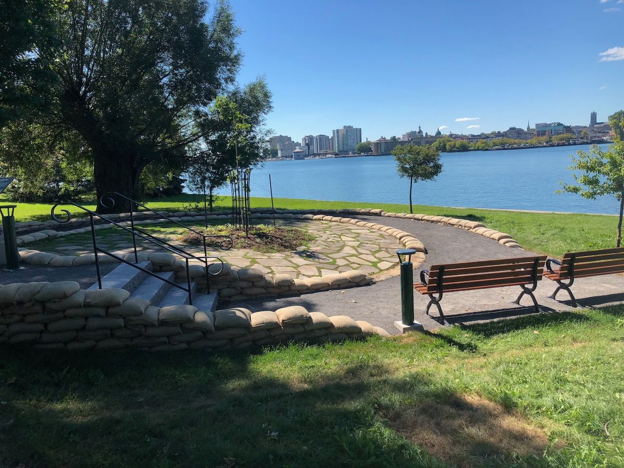 A park with a bench and stairs leading to a body of water.