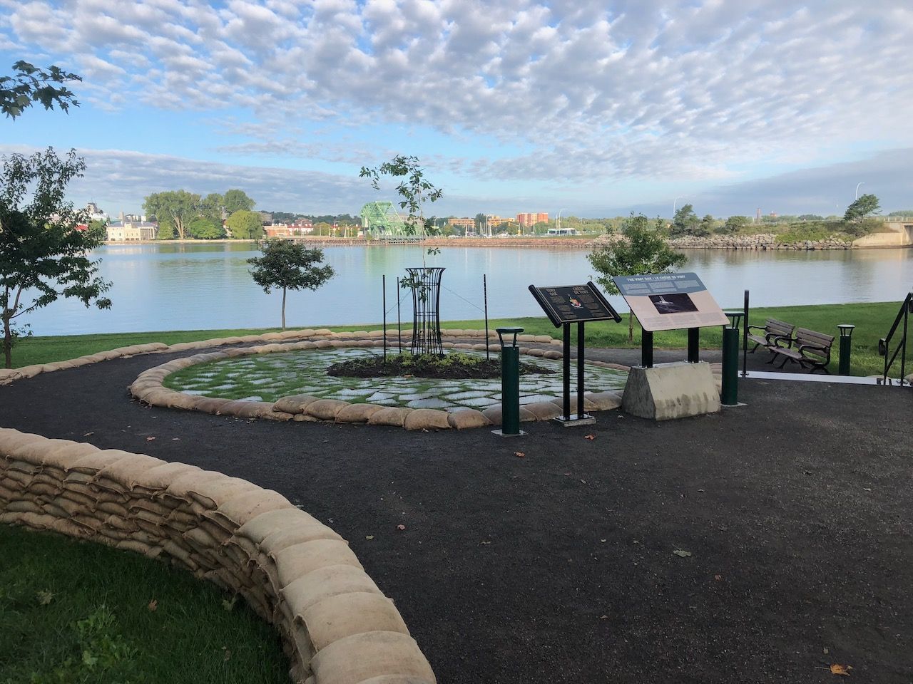 A park with a lake in the background and a sign in the foreground