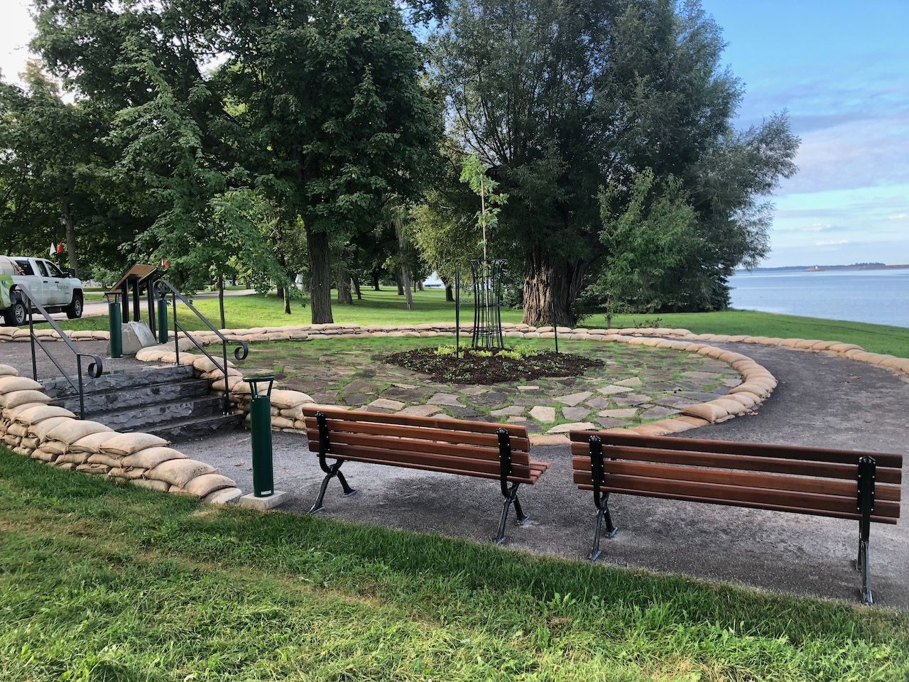 Three wooden benches are sitting in a park next to a body of water.