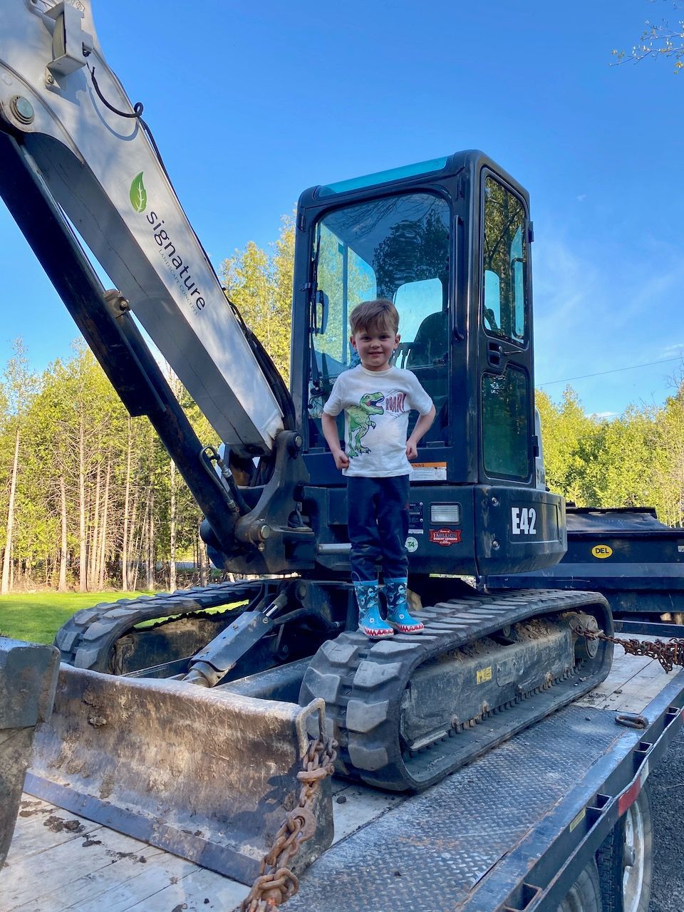 A little boy is sitting on the back of a bulldozer.