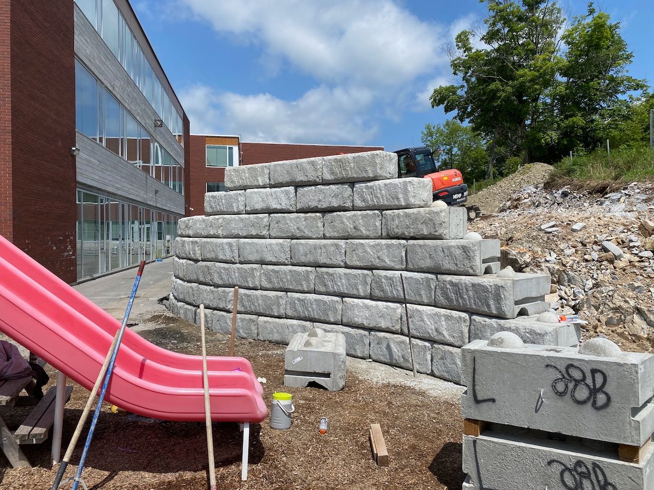 A pink slide is sitting next to a pile of concrete blocks.