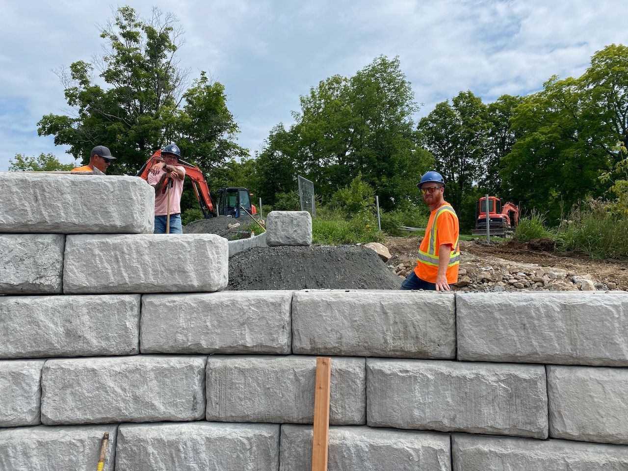 A group of construction workers are working on a stone wall.