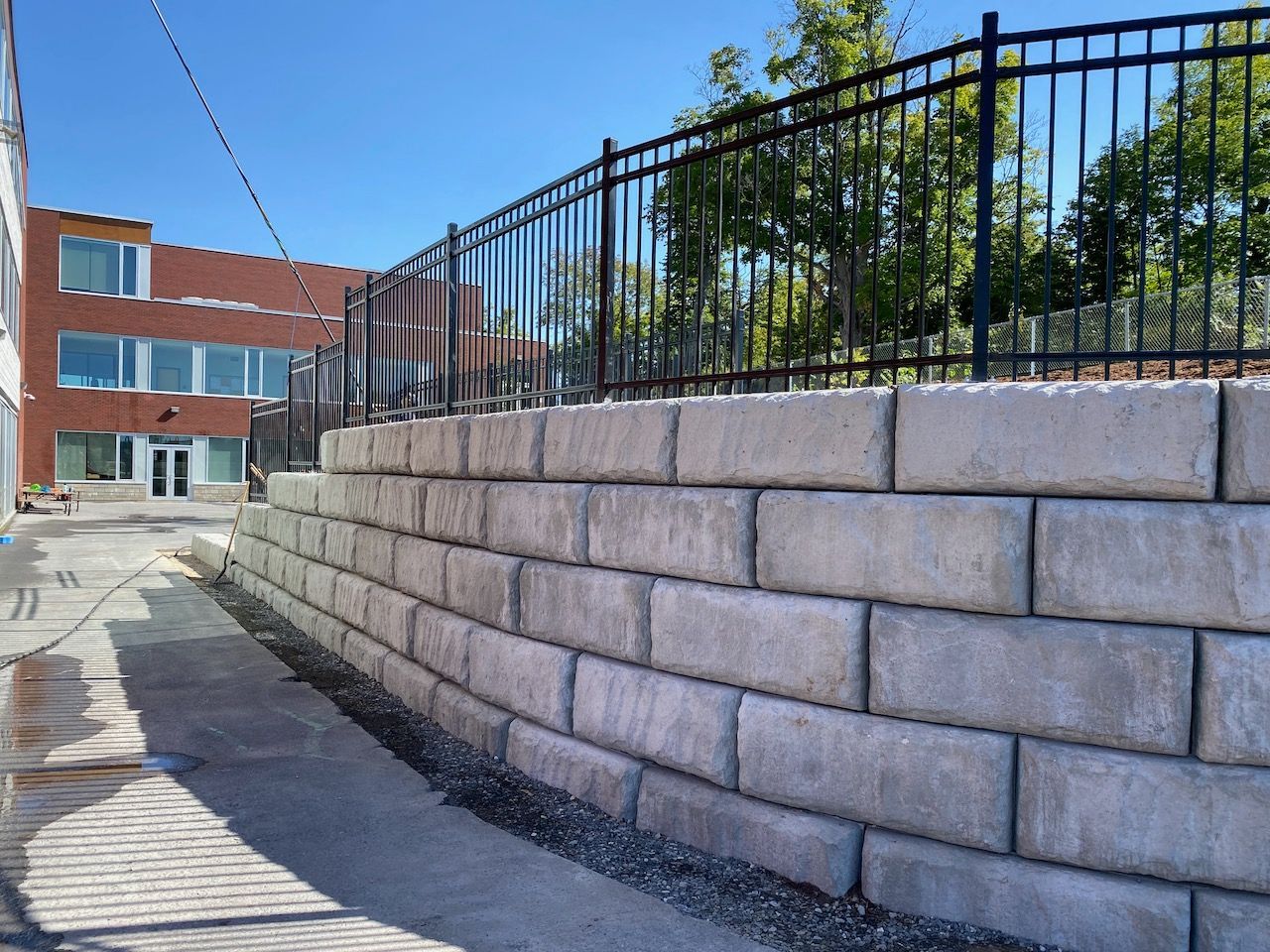 A brick wall with a metal fence behind it