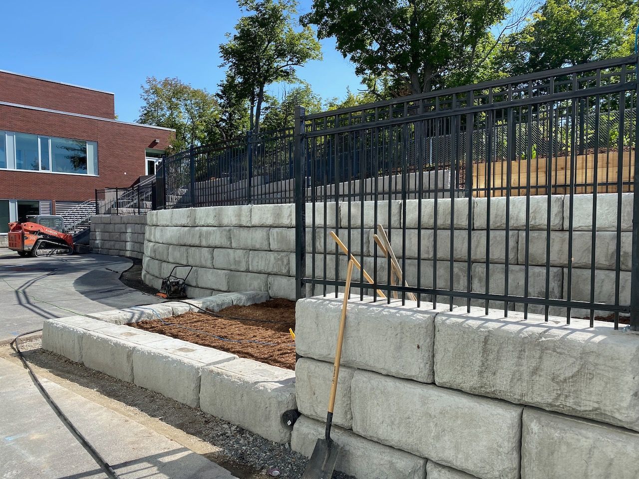 A shovel is leaning against a wall next to a fence.