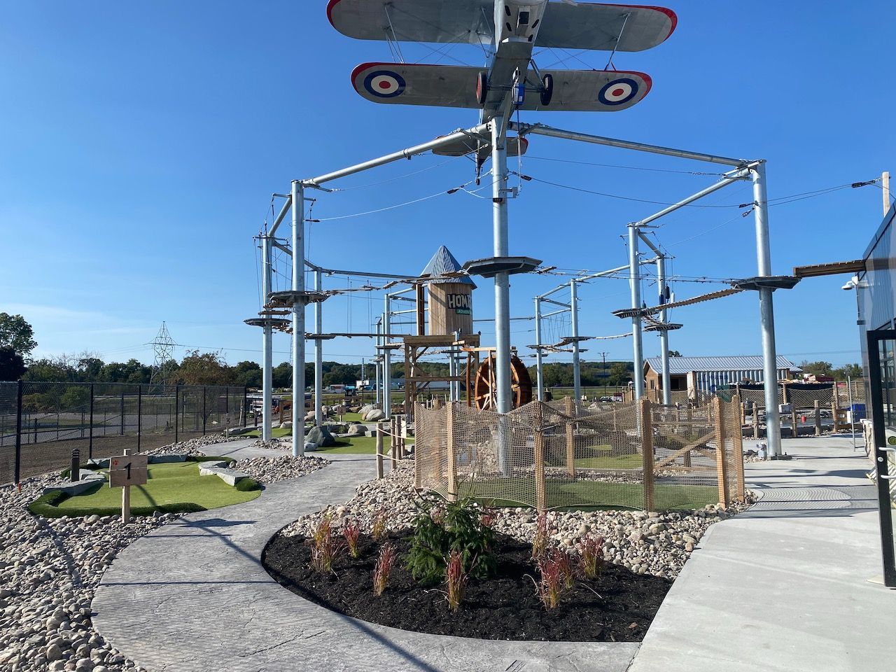 A ropes course with a plane hanging from the top of it.