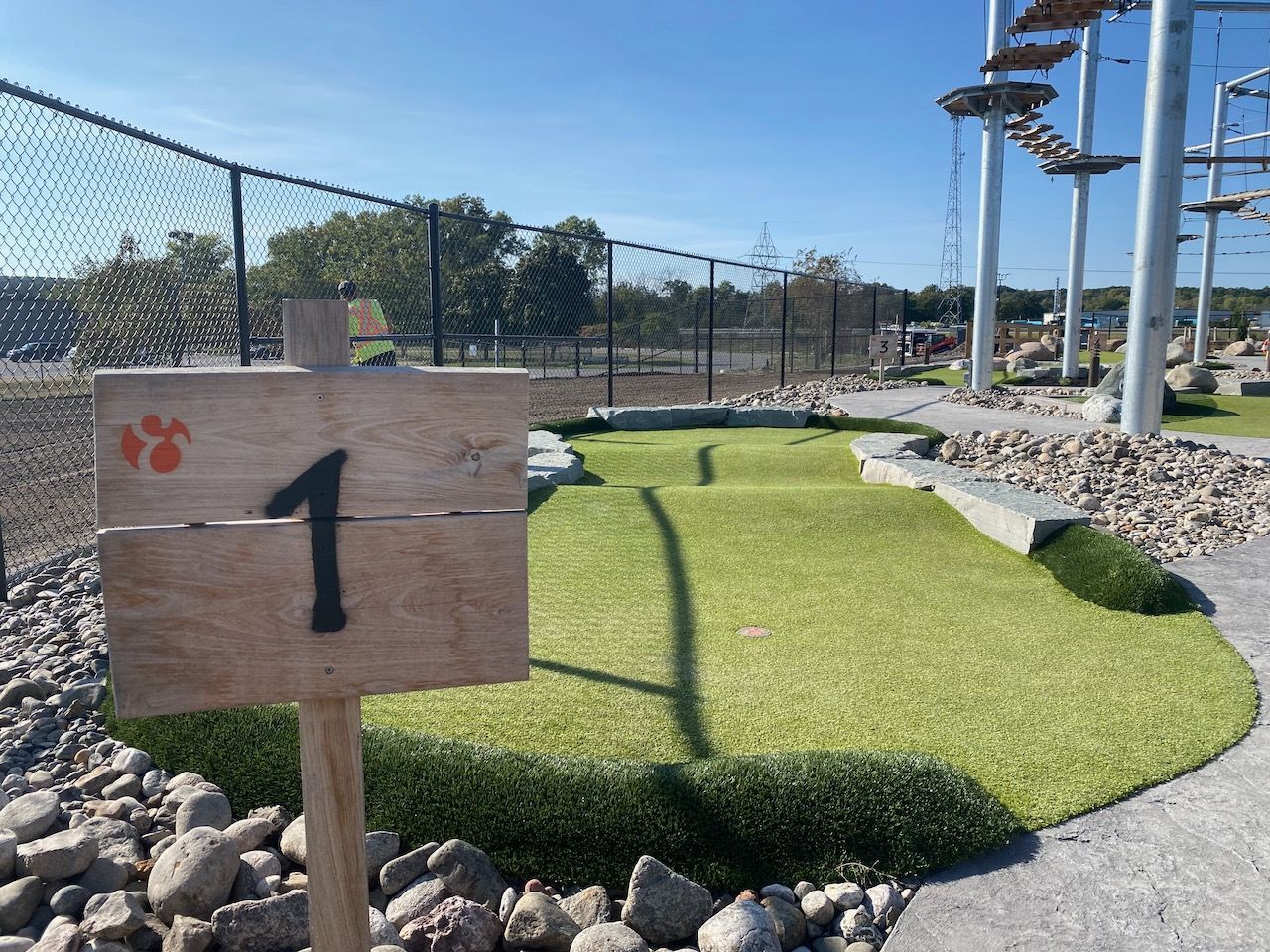 A wooden sign with the number 1 on it is on a golf course.