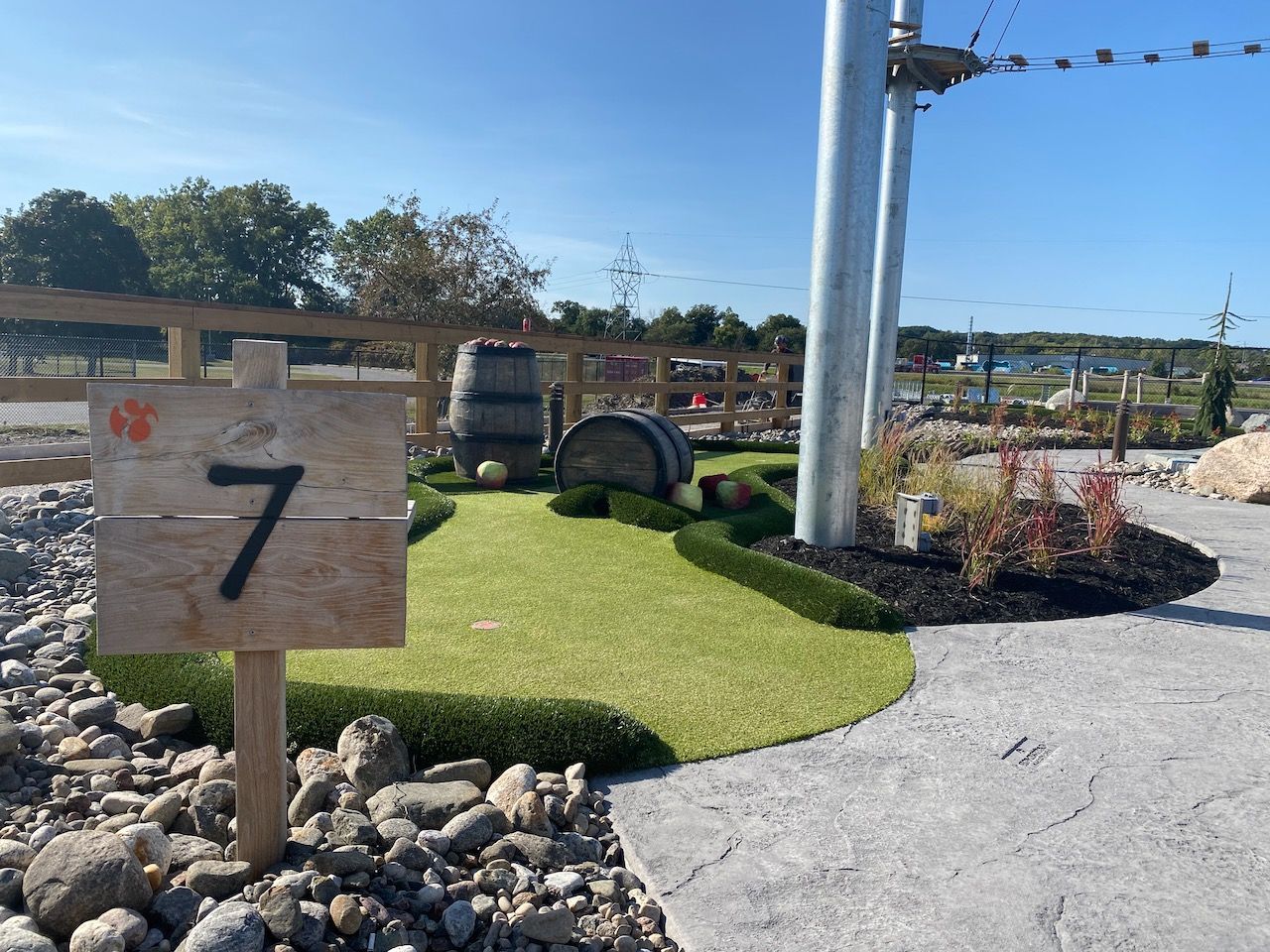 A wooden sign with the number 7 on it is in front of a golf course.